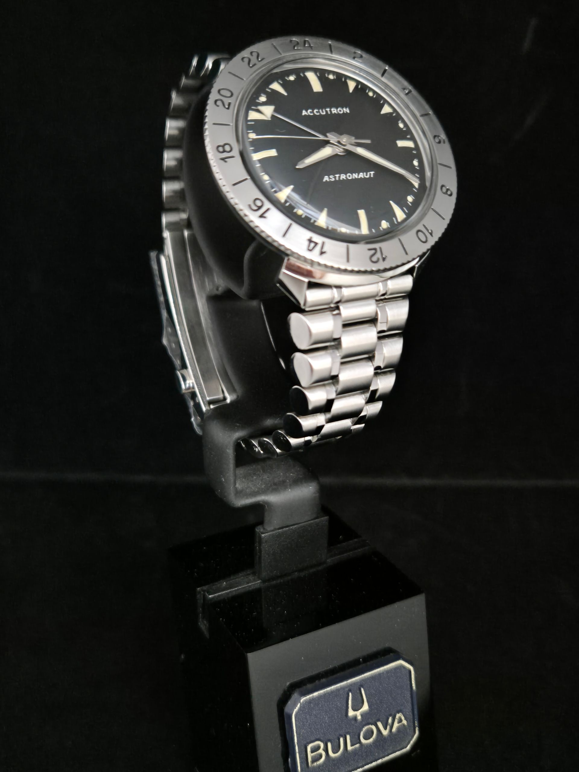 Bulova wristwatch on a display stand, with silver band and dark dial