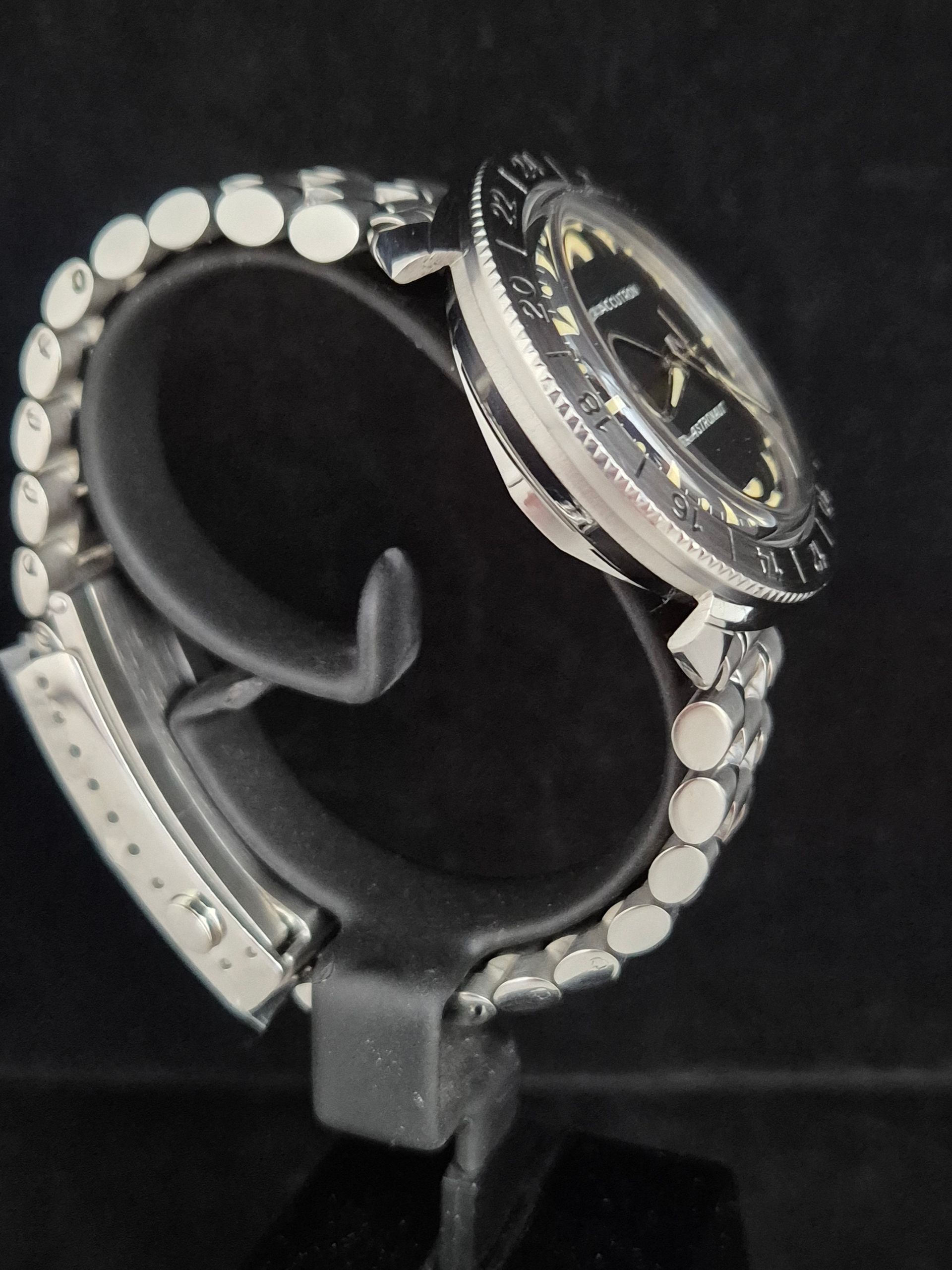 Black beaded bracelet with silver charm and dangling medallion on a display stand