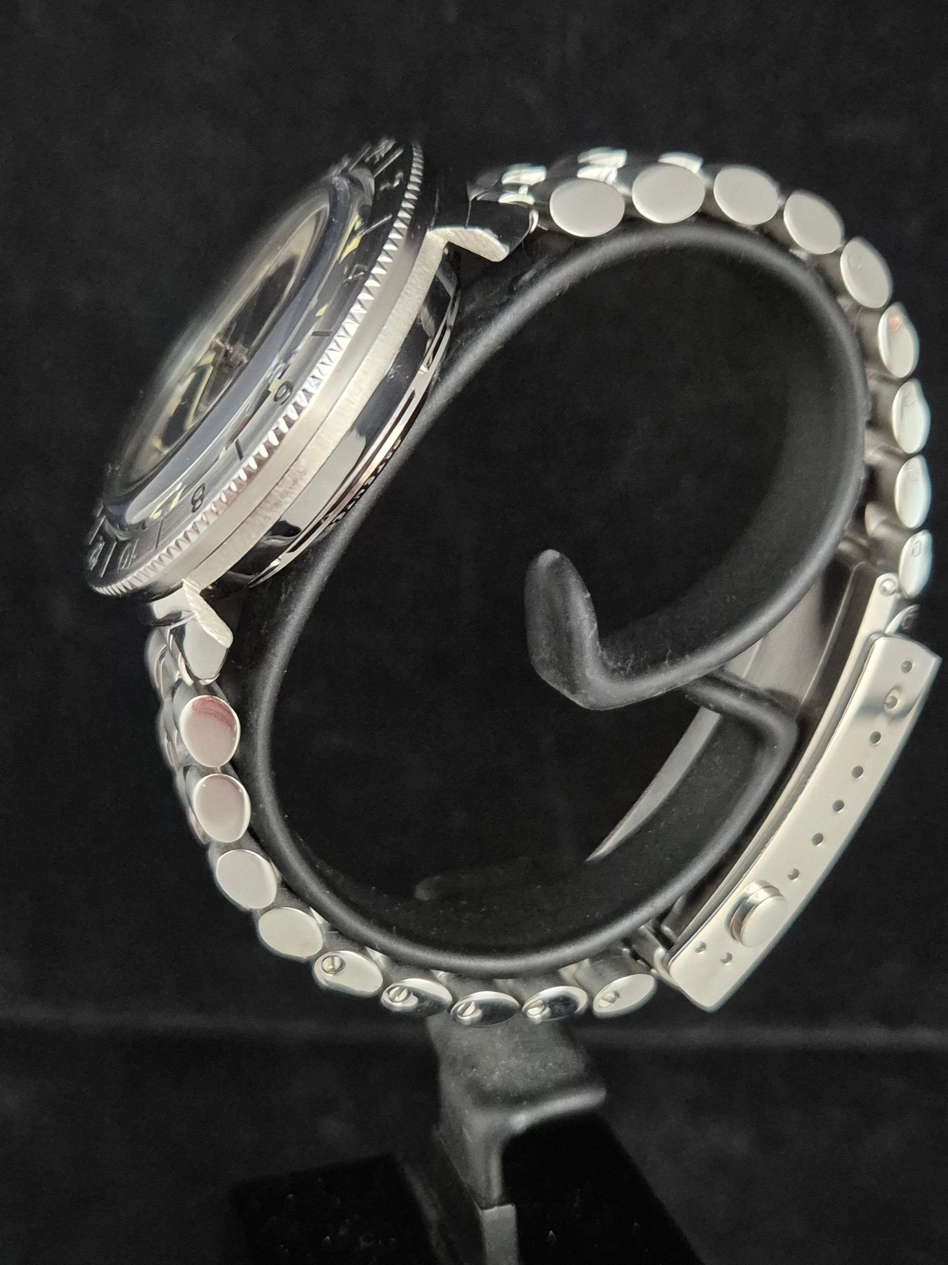 Black smartwatch with silver bezel and perforated strap on a display stand
