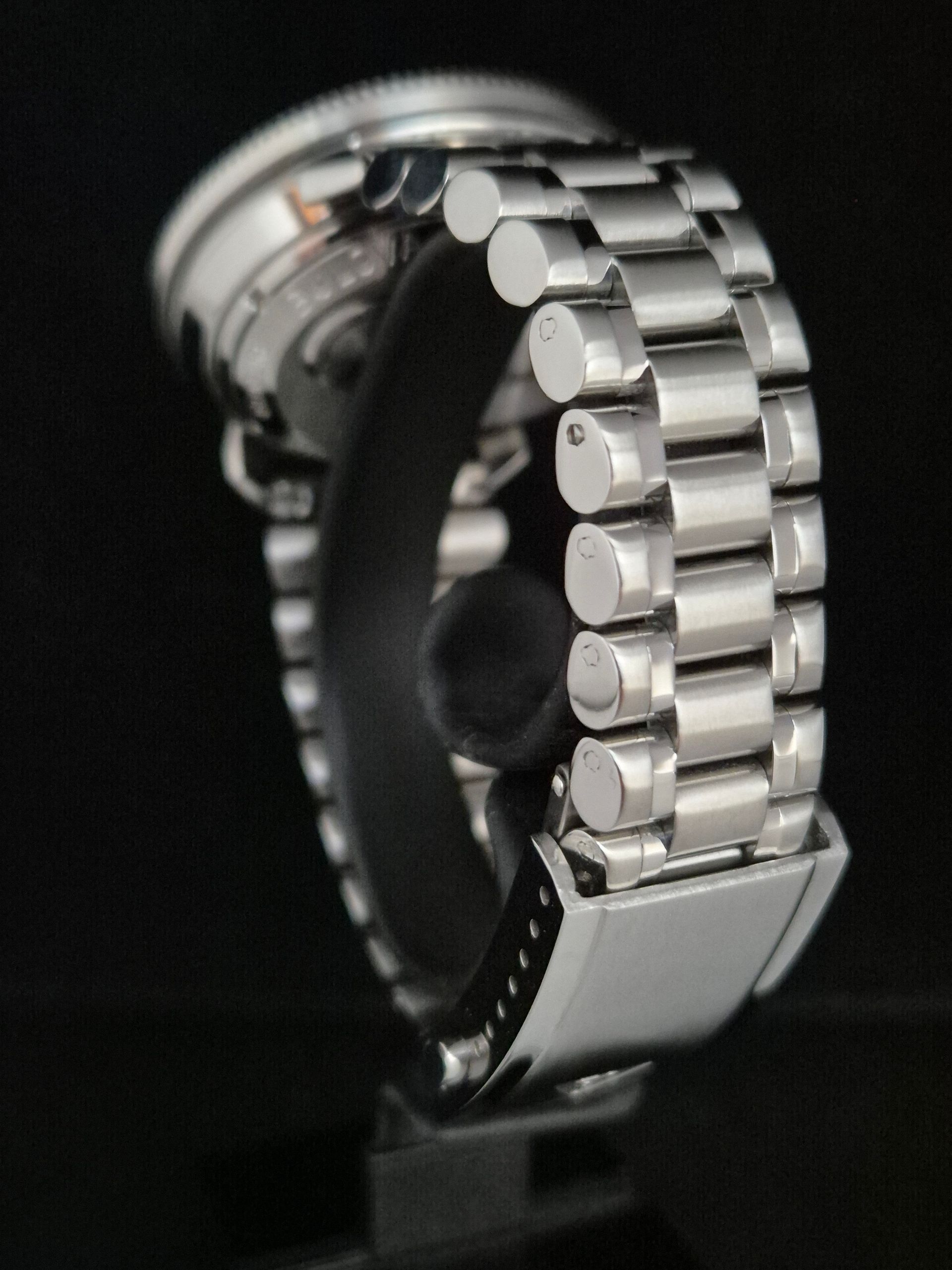 Close-up of a silver metal watch bracelet clasp on a black background