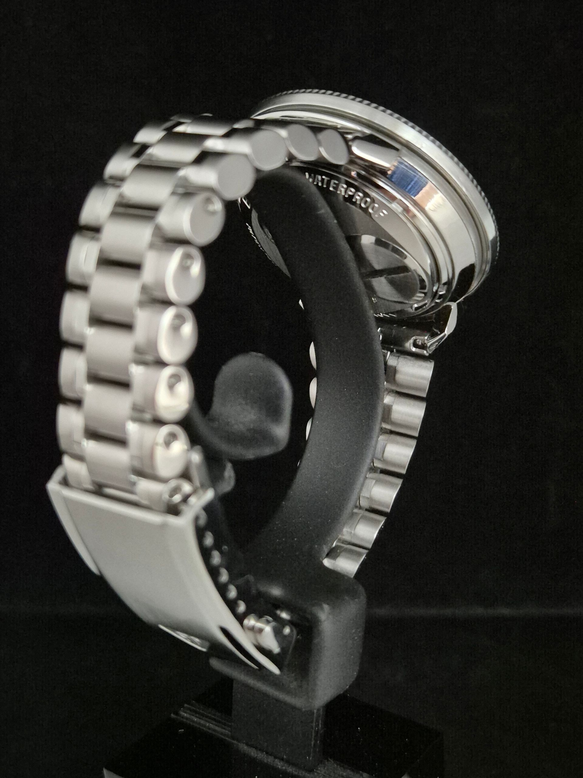 Silver bracelet watch on a black display stand against a dark background