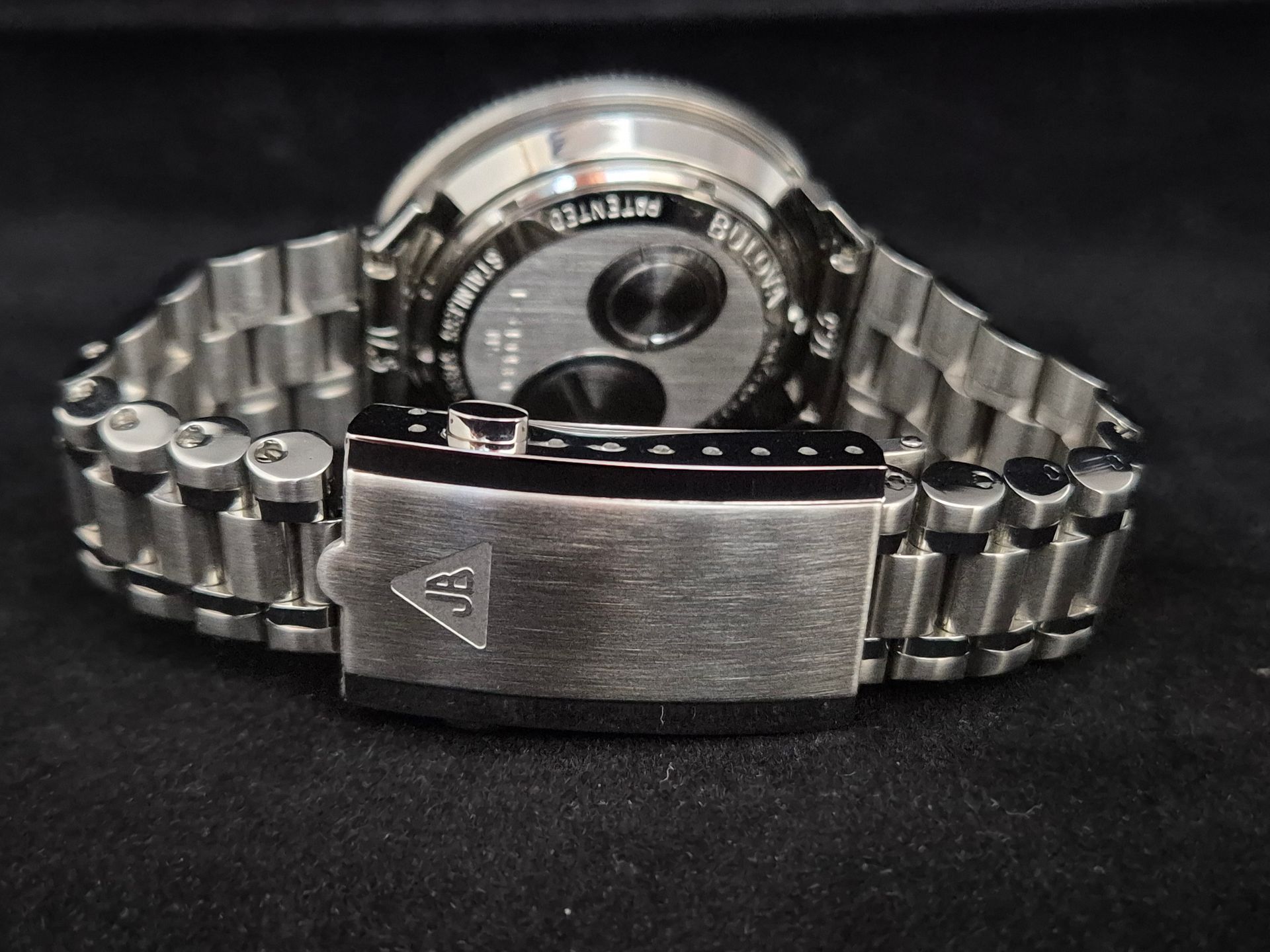 Silver wristwatch with metal band and clasp, shown against a black background.