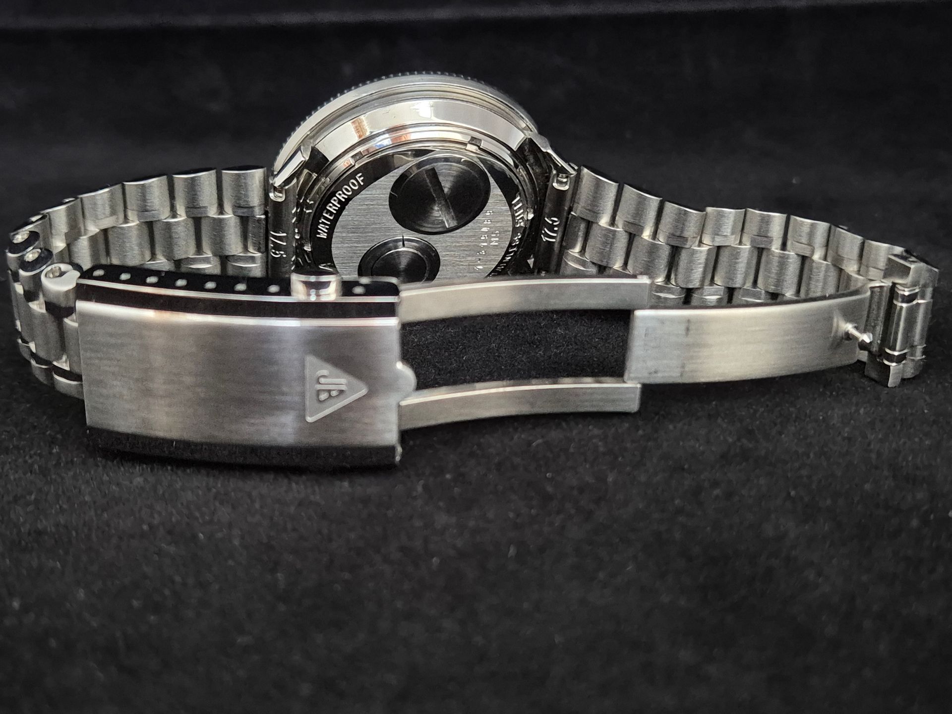 Silver metal wristwatch with open bracelet and clasp, shown close up on a dark background