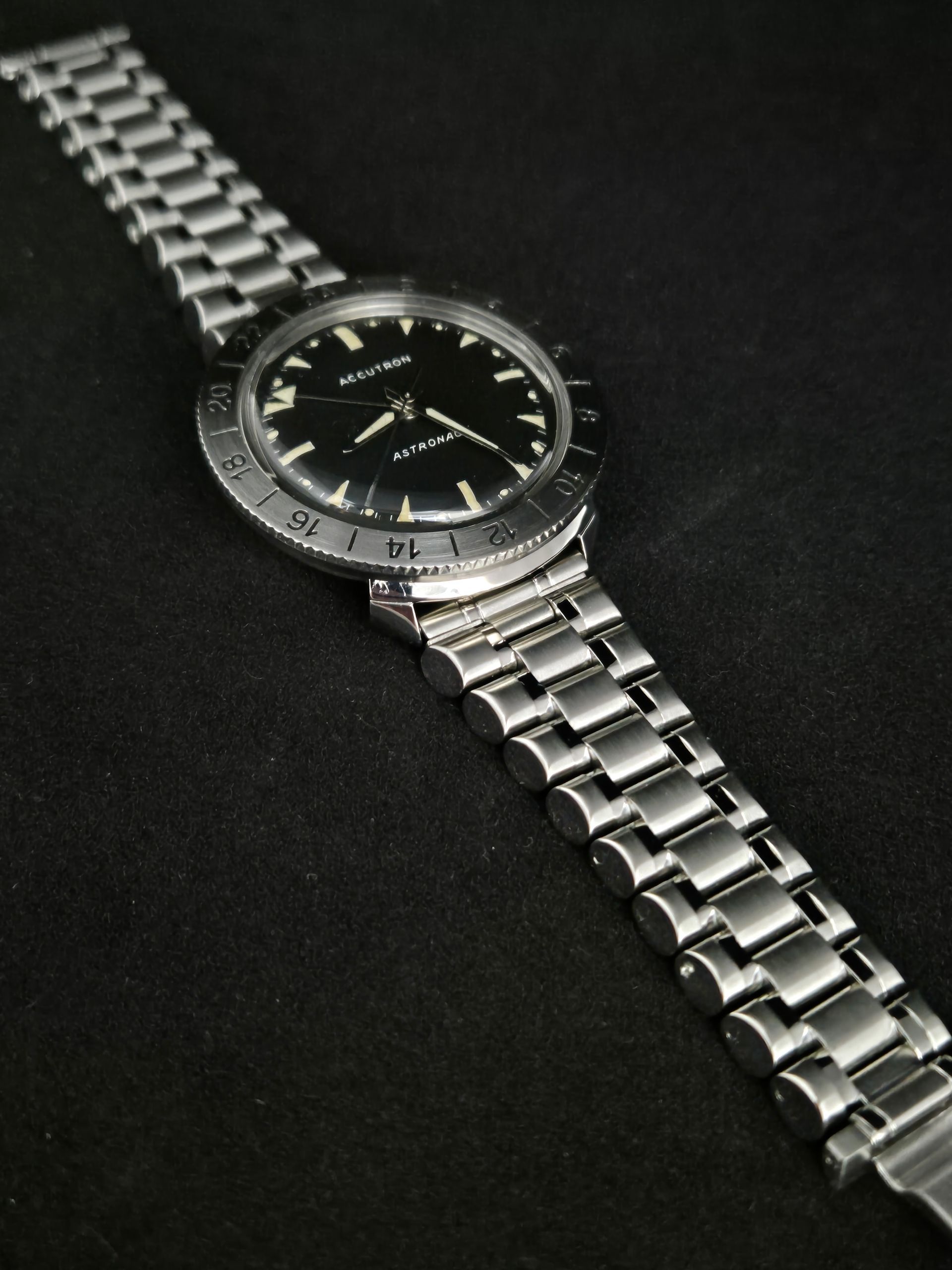 Silver wristwatch with a black dial on a black background