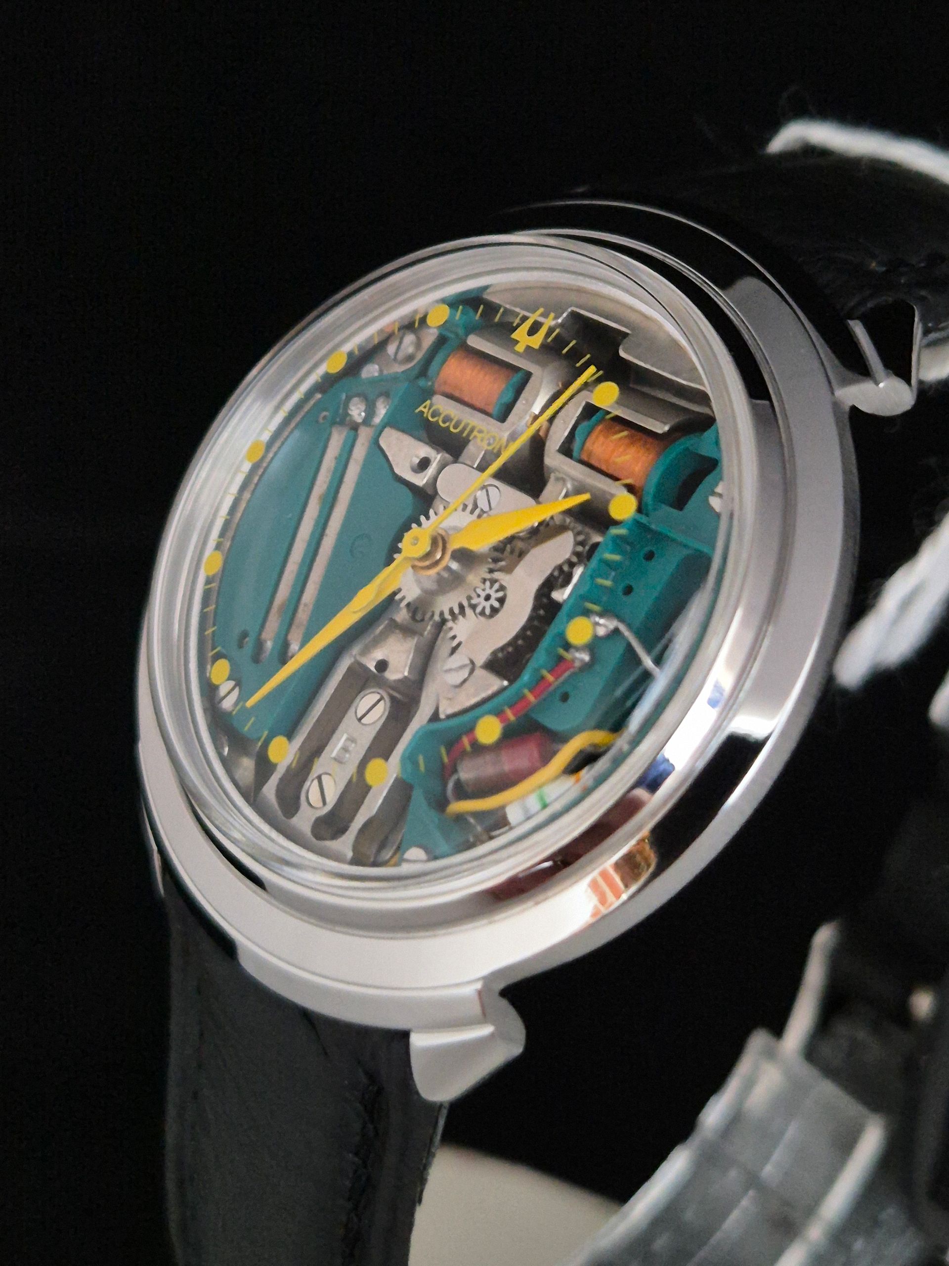 Close-up of a transparent skeleton wristwatch with yellow accents and a black strap on a dark background