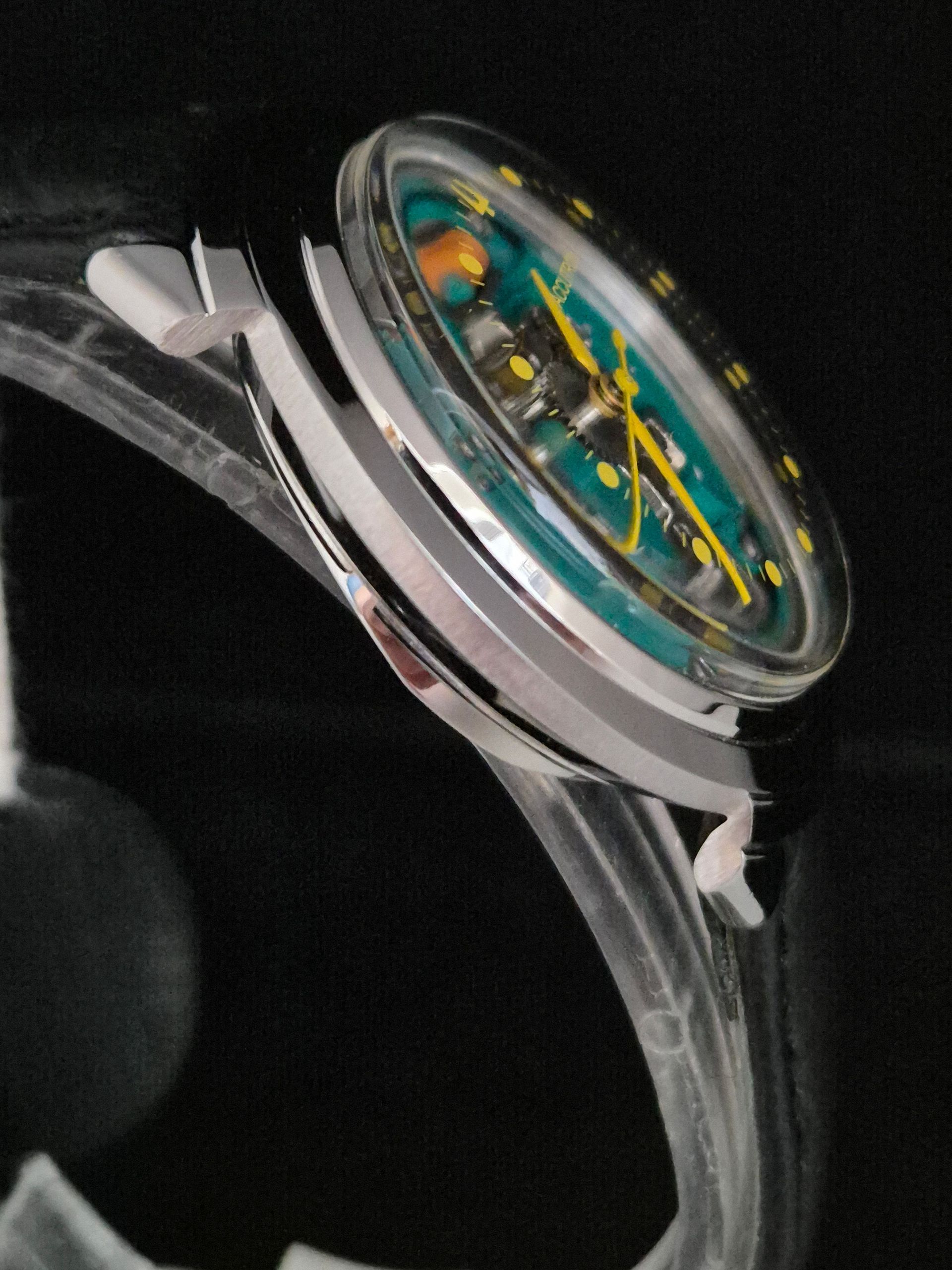 Close-up of a transparent wristwatch with a colorful blue and yellow dial on a black background