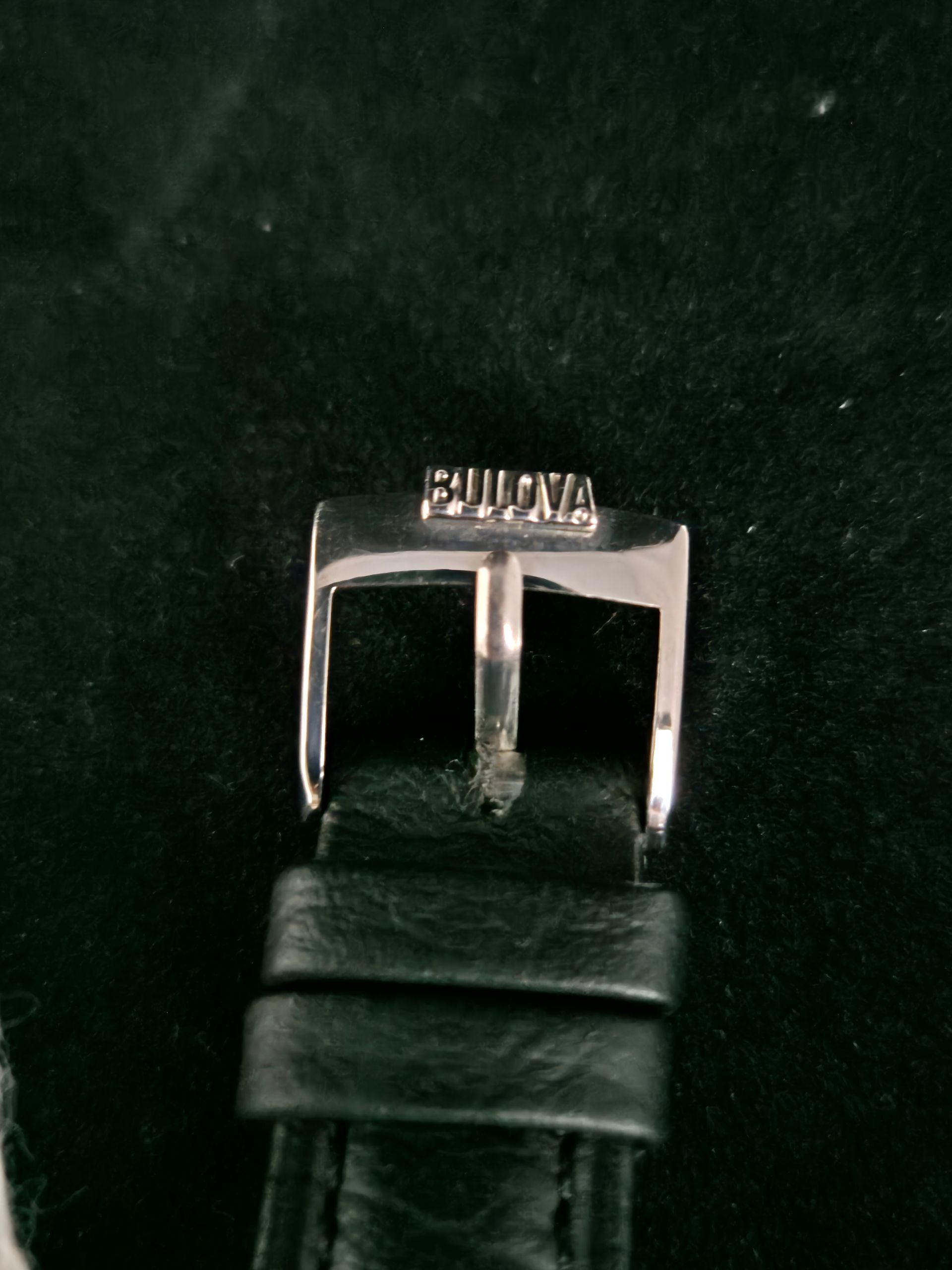 Black leather watch strap with a silver buckle on a dark background