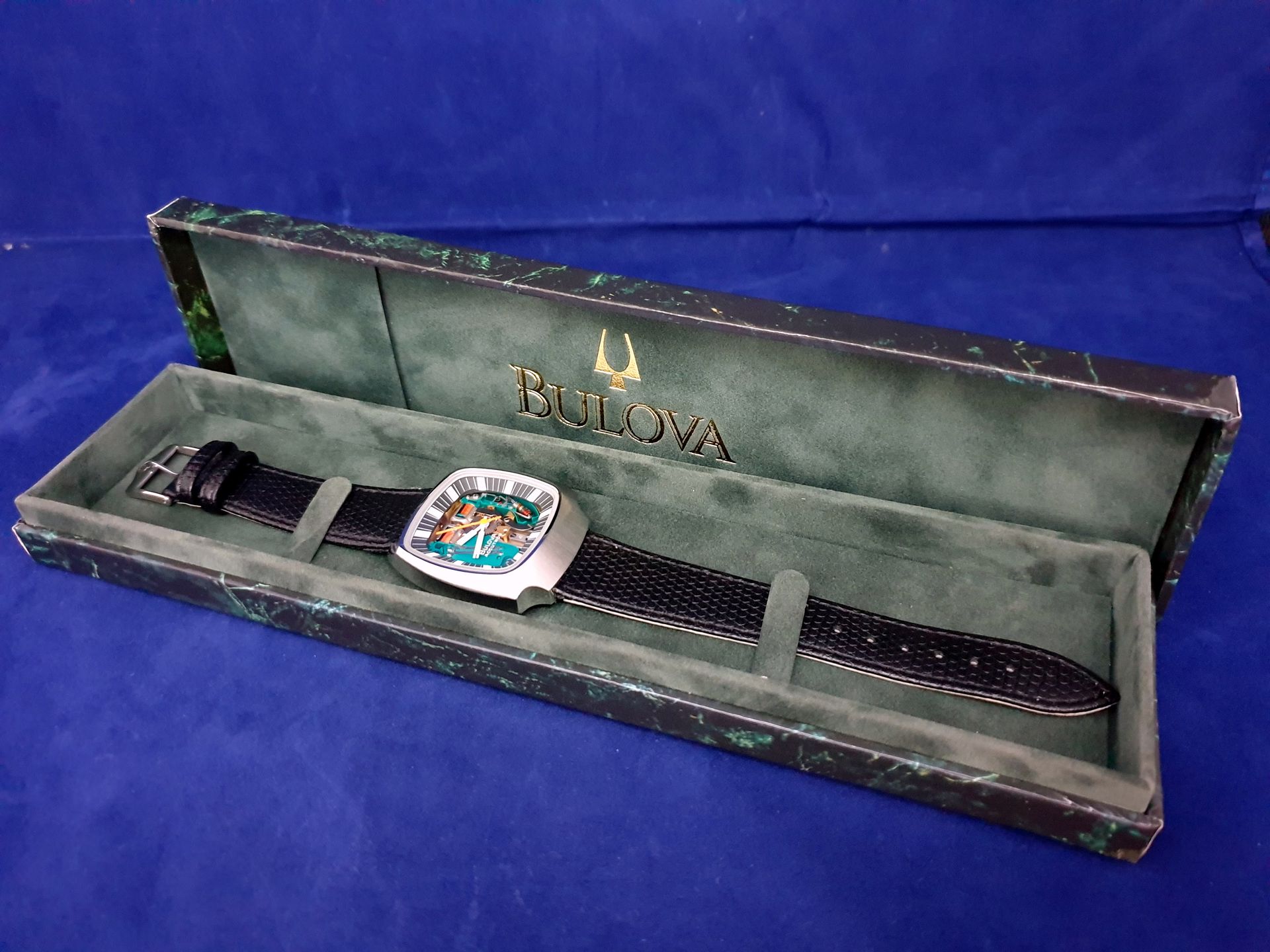 Bulova wristwatch in a green display case on a blue background