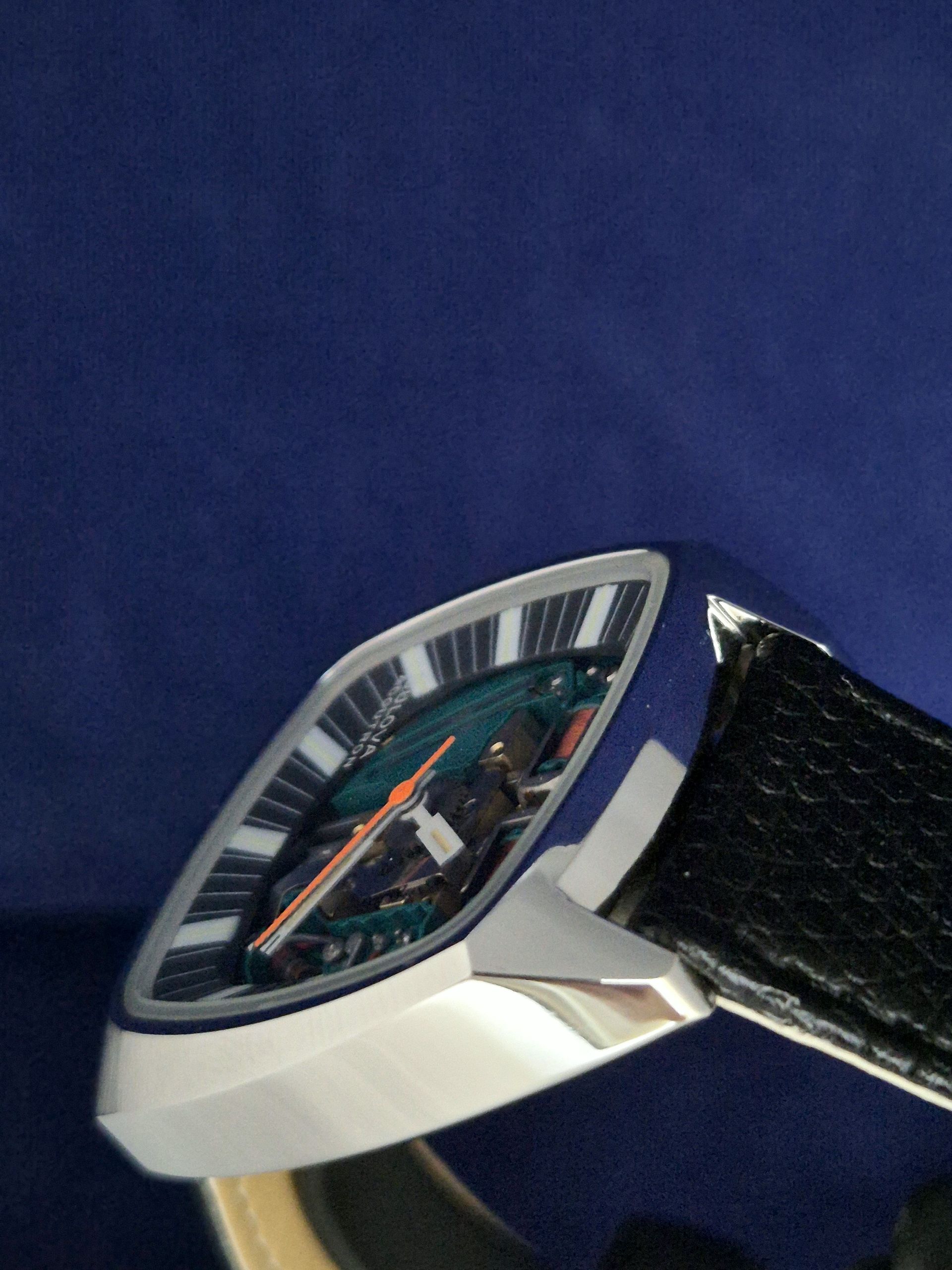 Close-up of a silver wristwatch with a black leather strap on a blue background