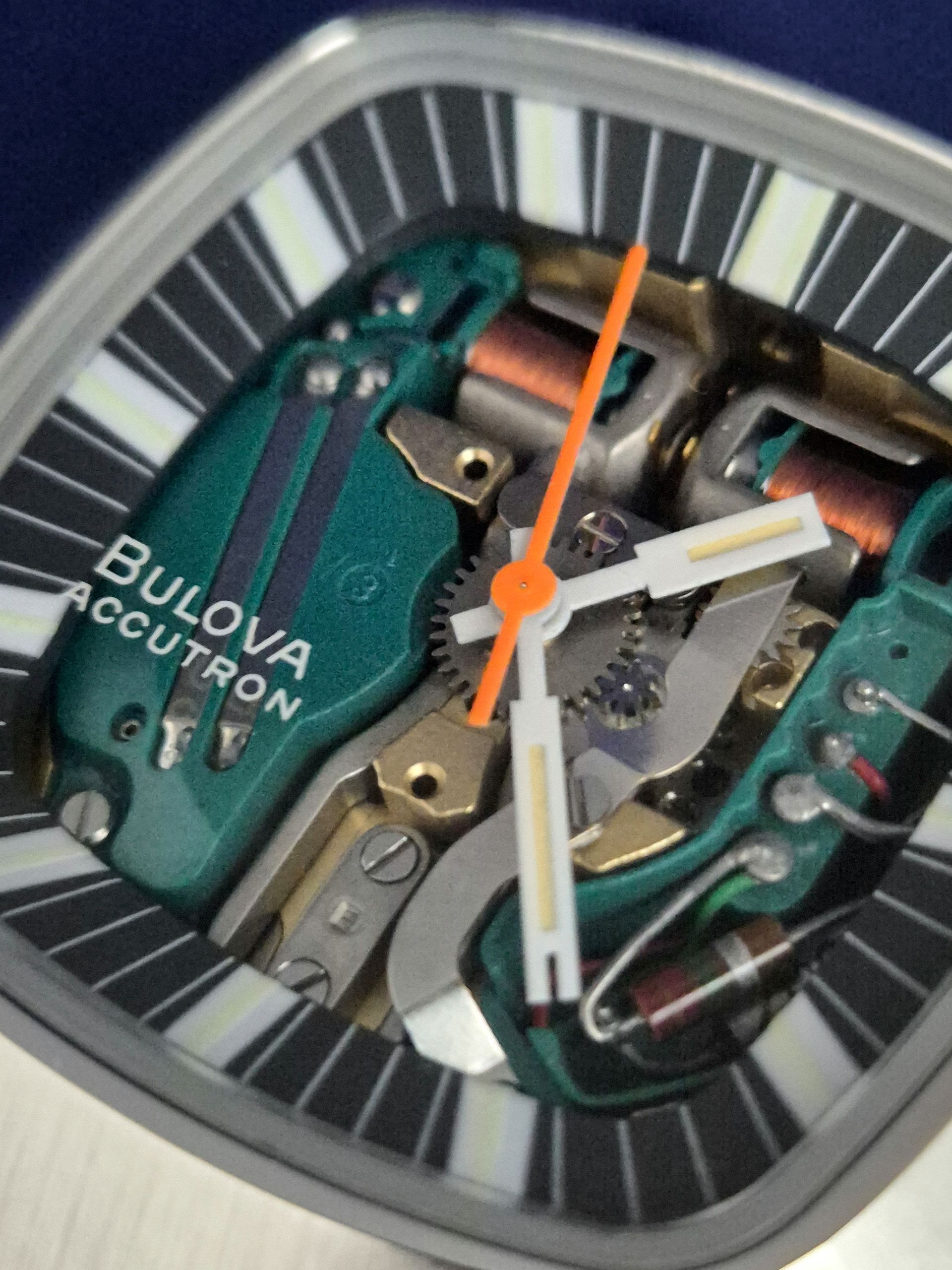 Close-up of a Bulova Accutron watch face with exposed mechanical components and orange hands