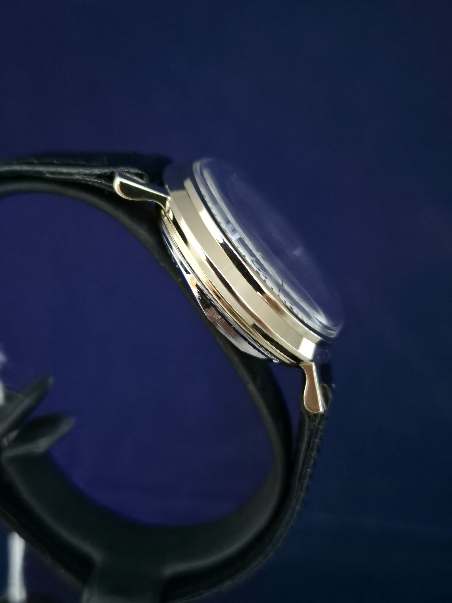 Silver wristwatch with black strap on a dark blue background
