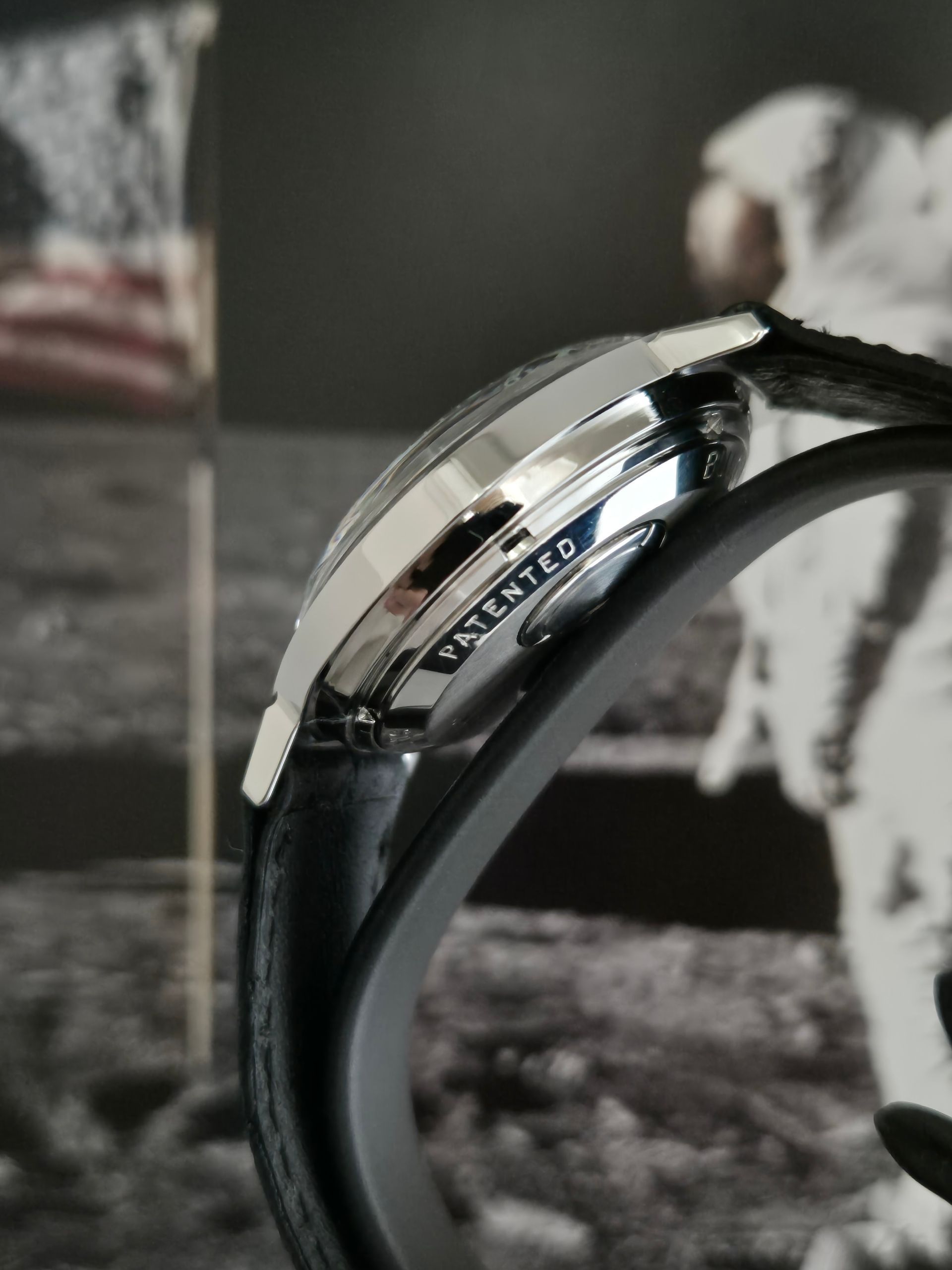 Close-up of a silver wristwatch on a black band against a grayscale background.