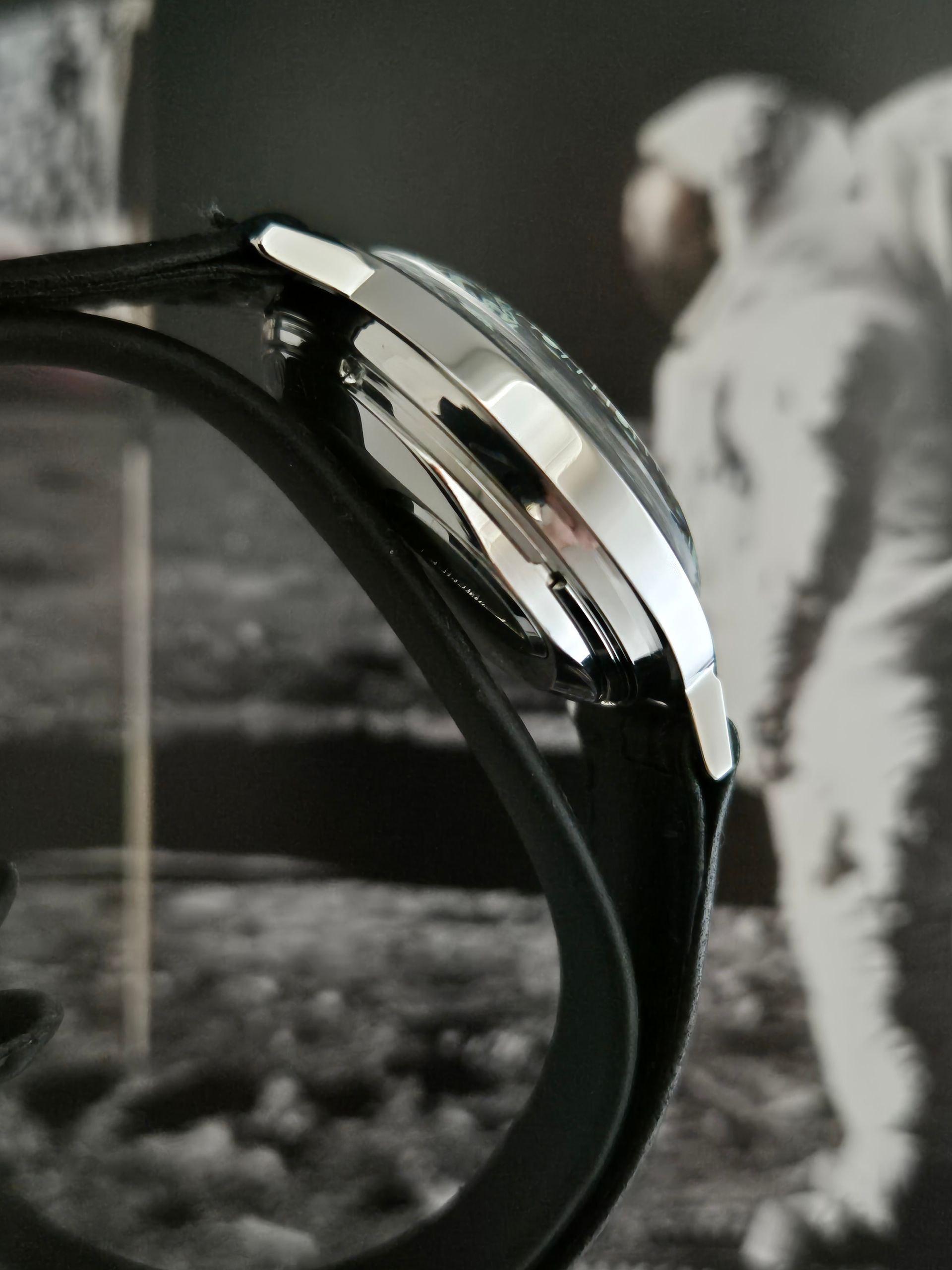 Close-up of a black wristwatch with a silver bezel against a blurred black-and-white background