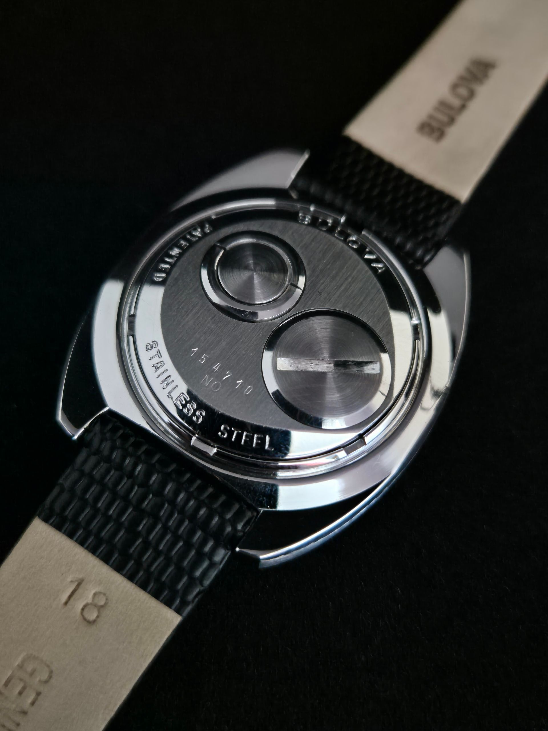 Close-up of a luxury wristwatch back with black strap and engraved silver case back.