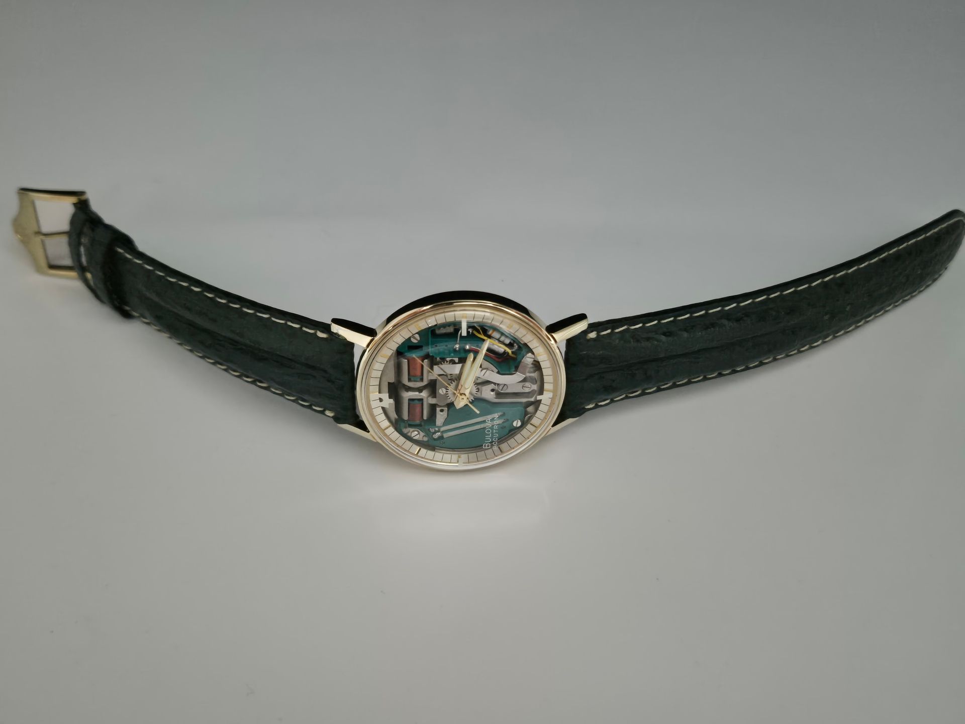 Green leather bracelet with a round silver watch face in the center