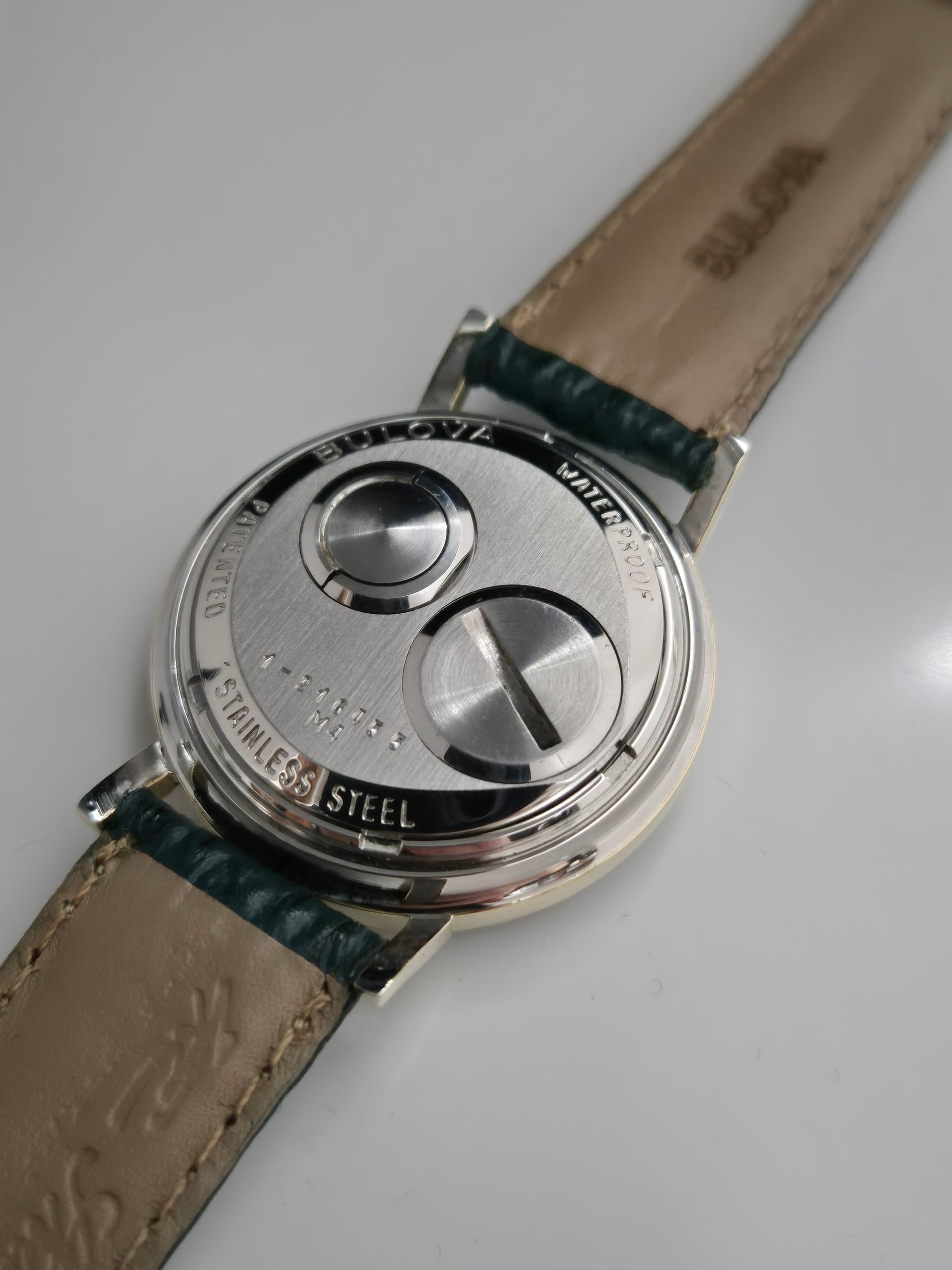 Close-up of a silver wristwatch with a beige leather strap on a light background