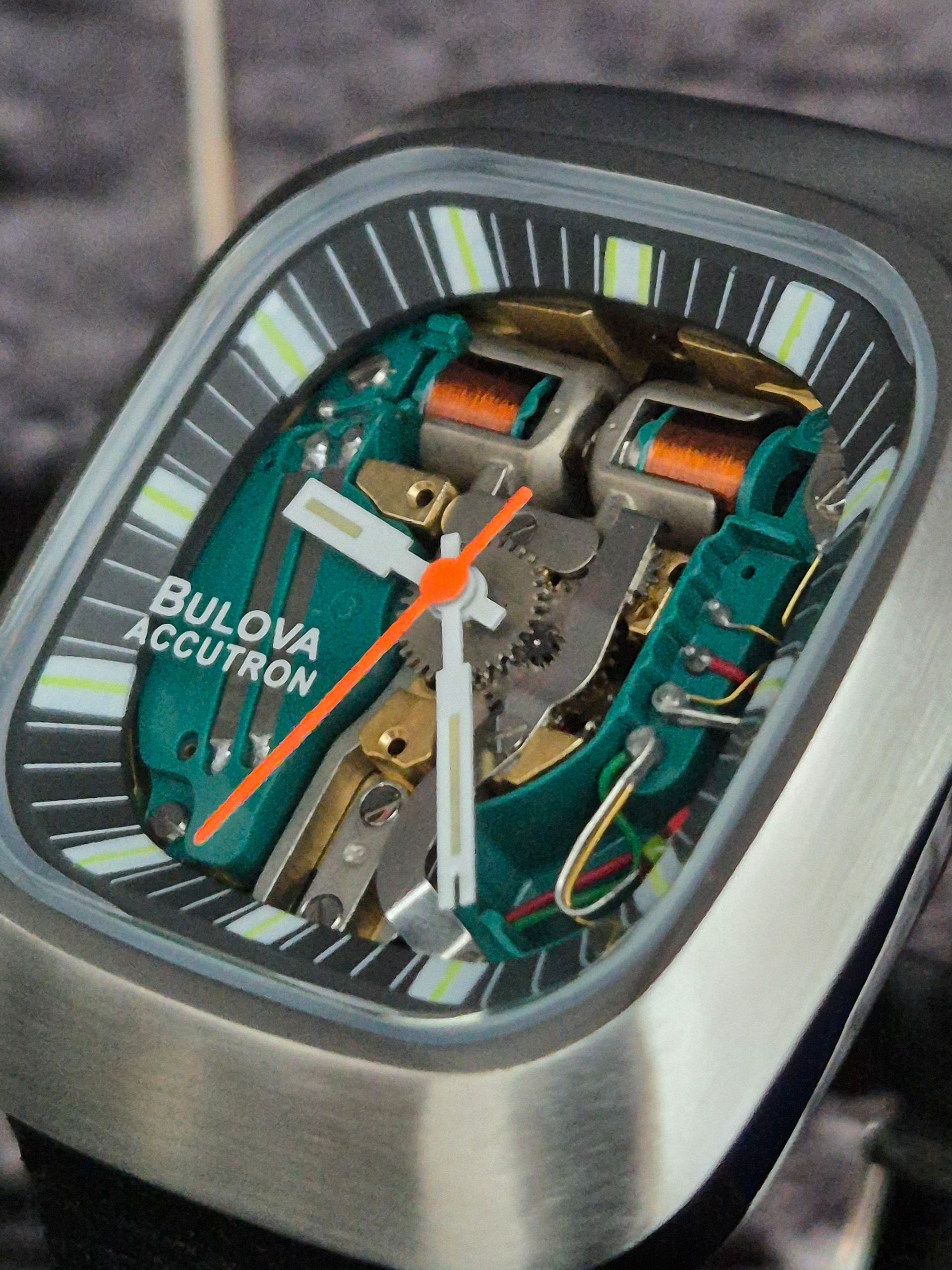 Close-up of a Bulova Curv watch with exposed mechanical movement and striped dial