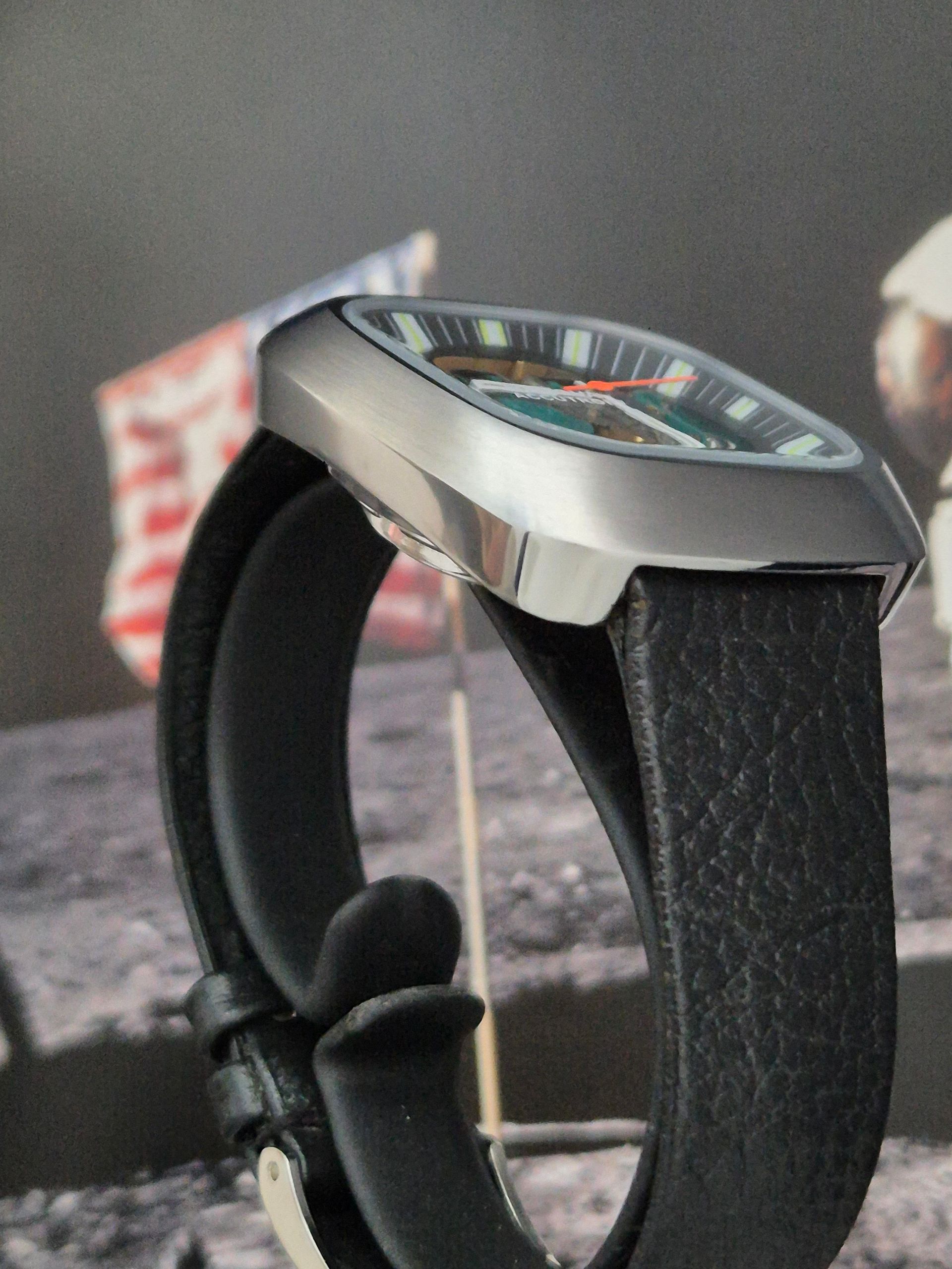 Black wristband device with a silver hexagonal face on a gray surface