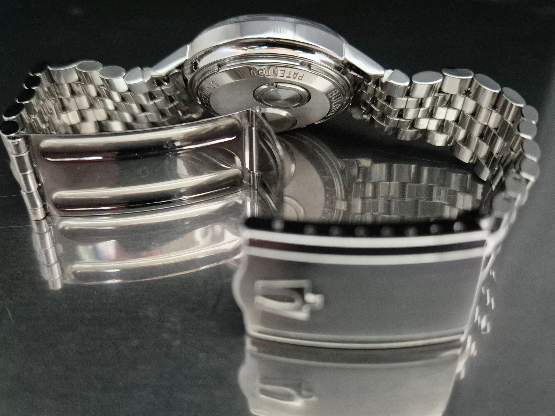 Close-up of a stainless steel wristwatch with a metal link bracelet on a dark surface