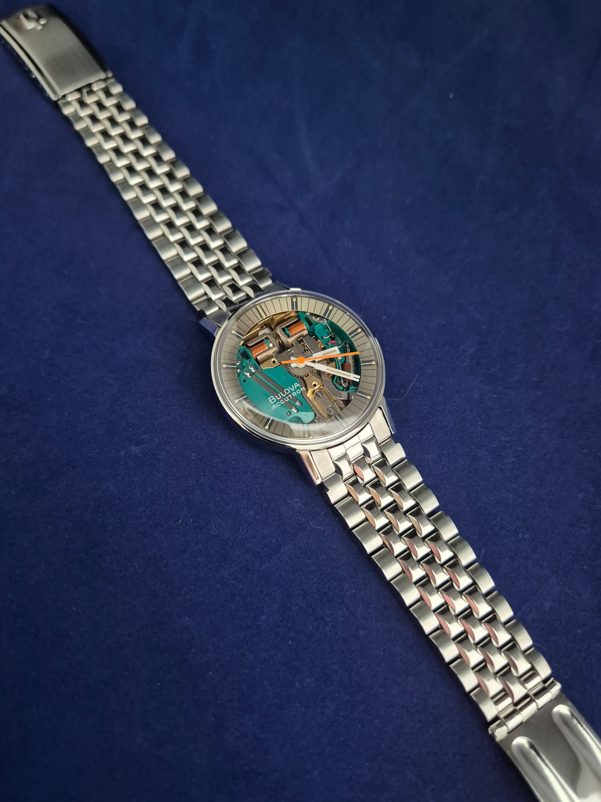 Silver wristwatch with turquoise dial on a dark blue background