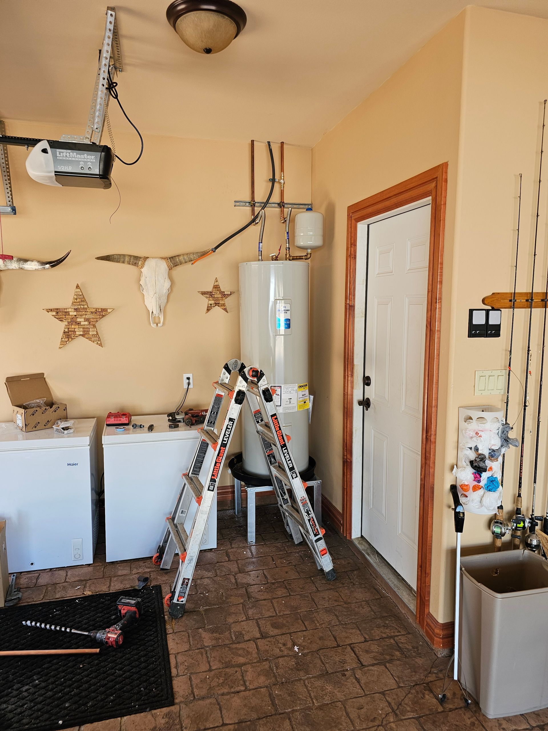 a laundry room with a water heater and a ladder