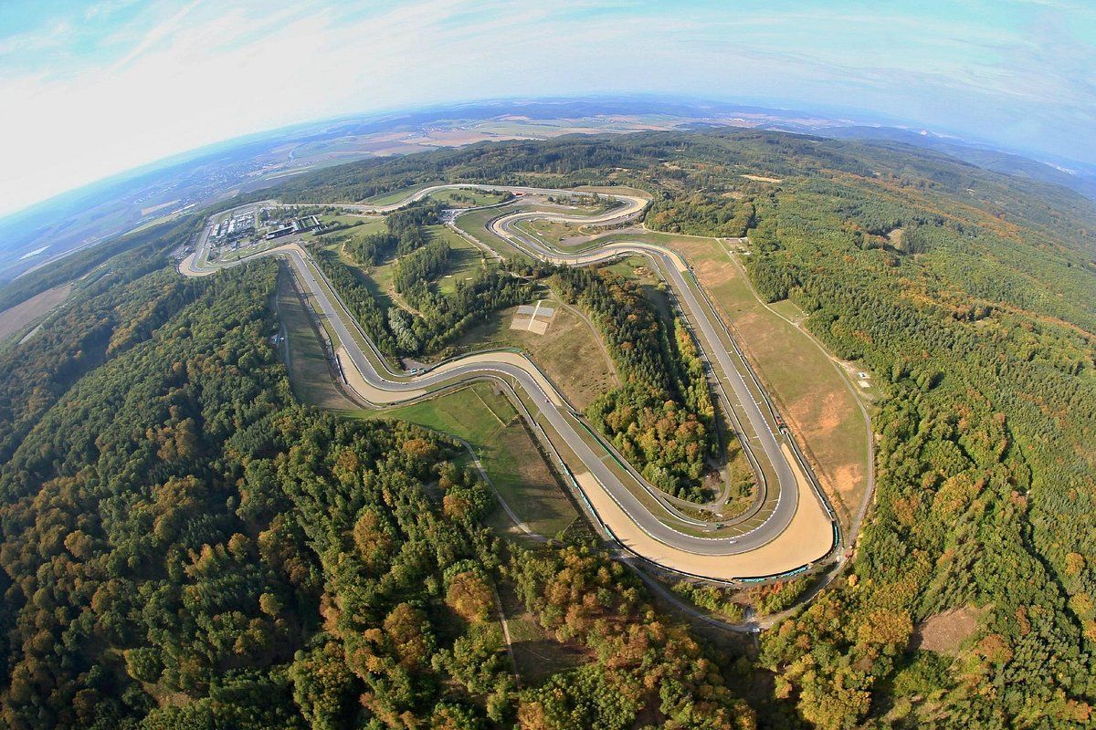 Luchtfoto van een kronkelende racebaan door een groen bos, mogelijk bedoeld voor autoraces.