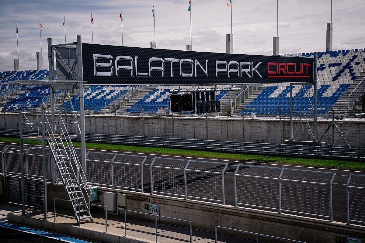 Bord voor het Balaton Park Circuit boven een lege tribune met blauw-witte stoelen.