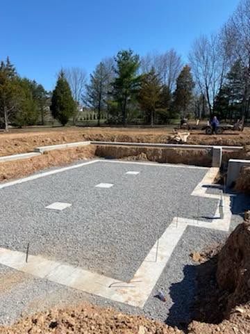 Rectangular gravel-lined pit in a landscaped yard, with stone edging and trees in the background