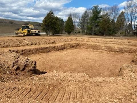 Construction site with a bulldozer grading a dirt lot under a cloudy sky