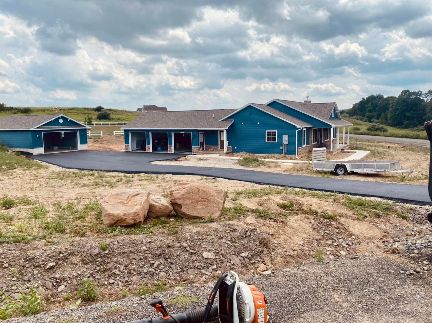New blue houses under construction in a rural lot with gravel roads and cloudy sky