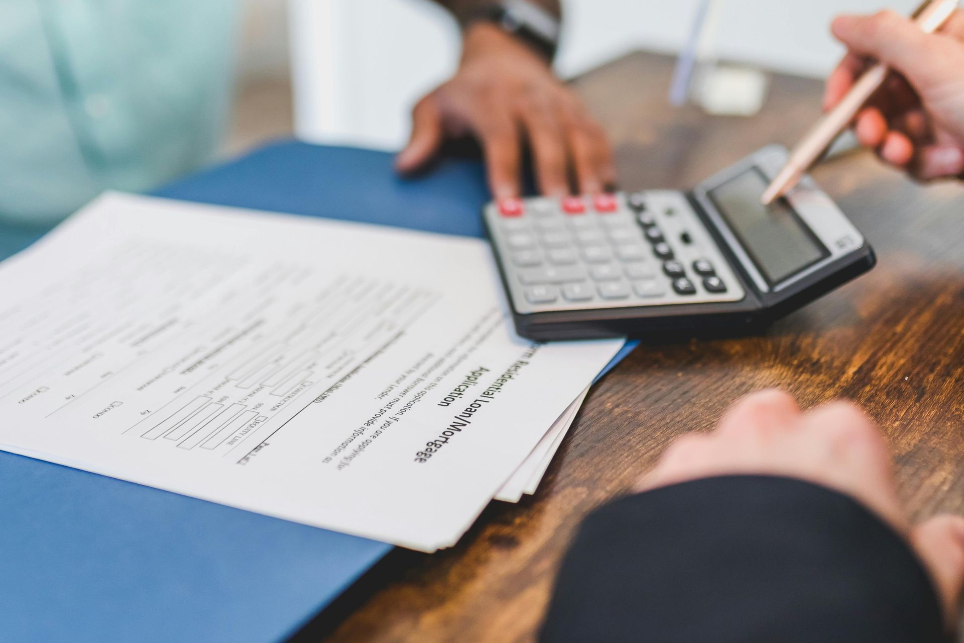 Person using a calculator to review paperwork on a desk