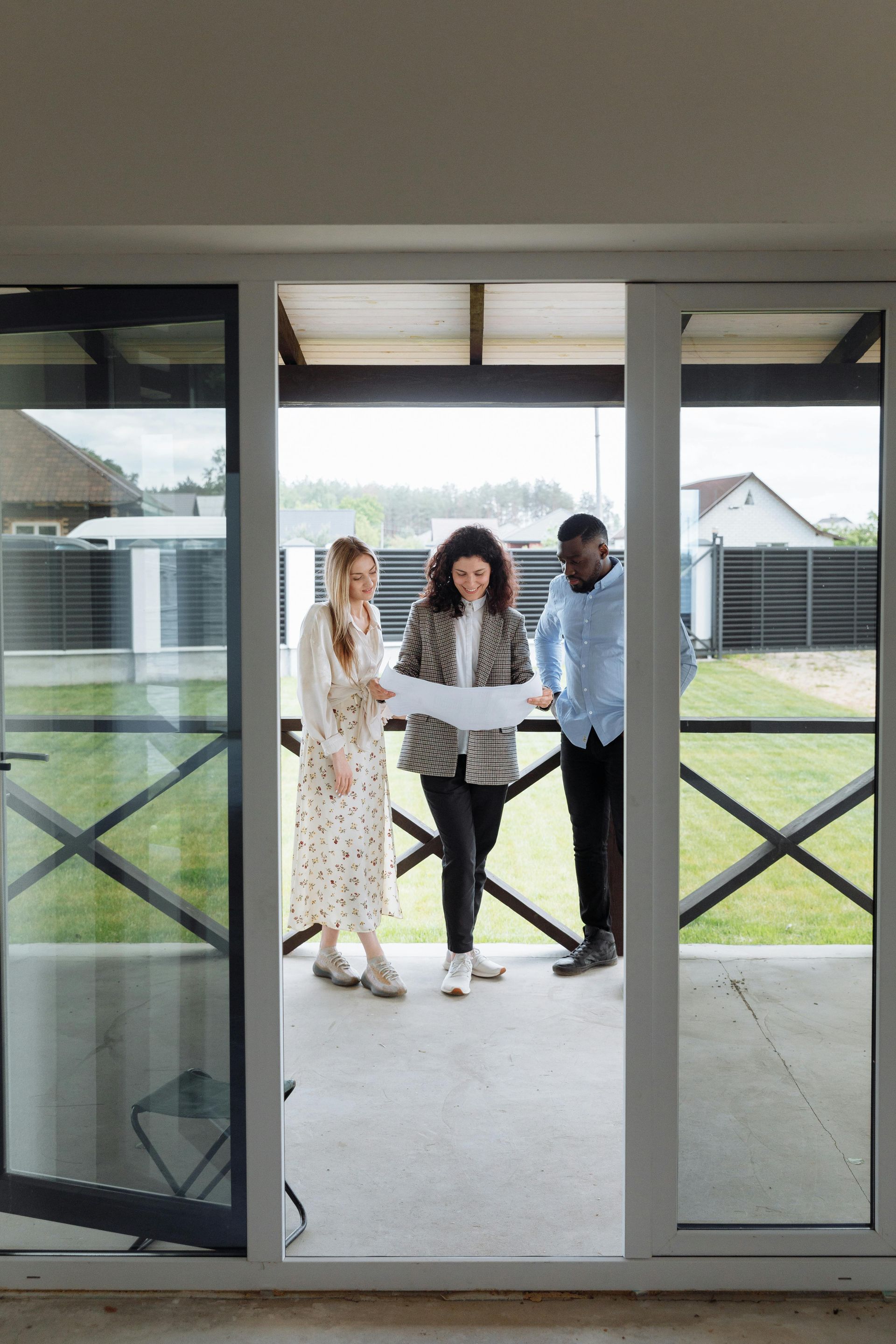Three people standing in a doorway, smiling in a bright backyard view
