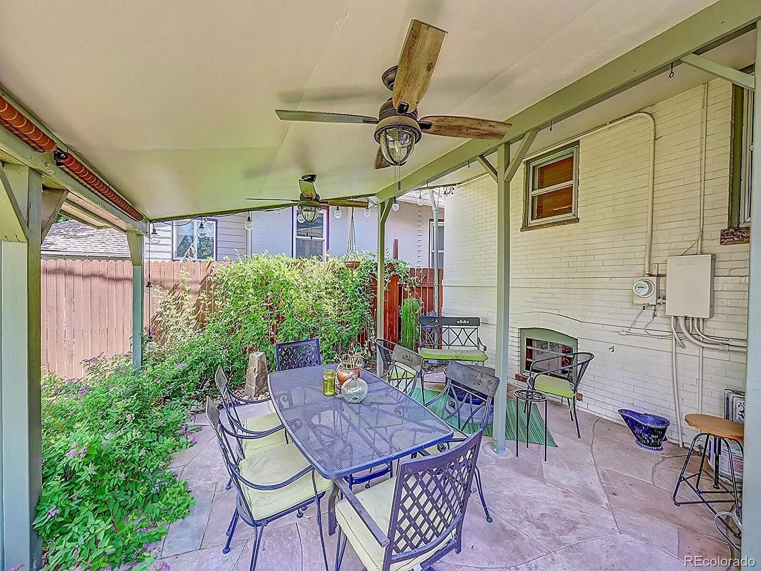A patio with a table and chairs and a ceiling fan.