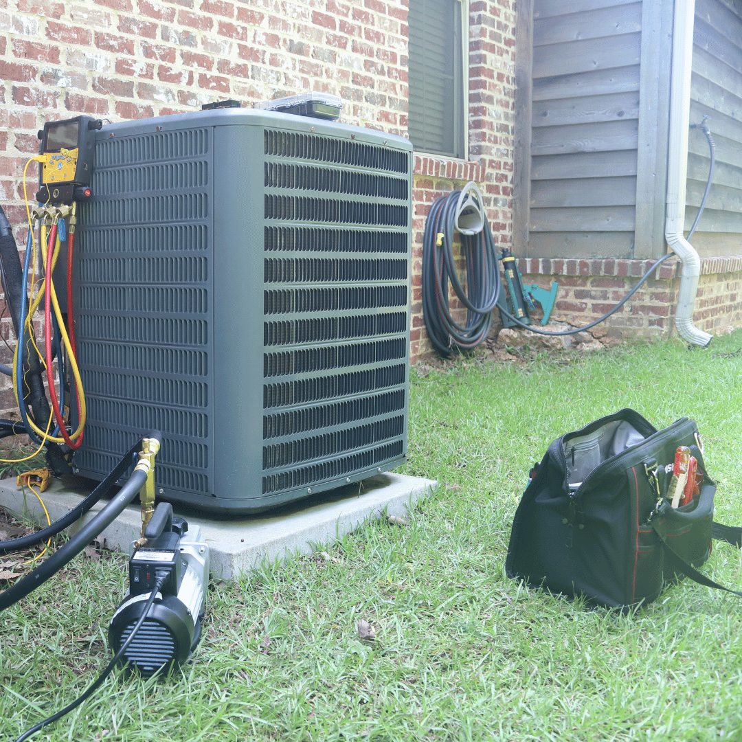 An air conditioner is sitting in the grass next to a brick building.
