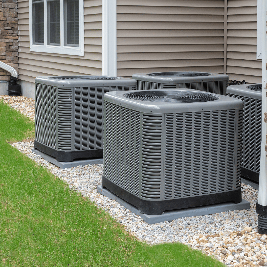 A row of air conditioners are sitting outside of a house.