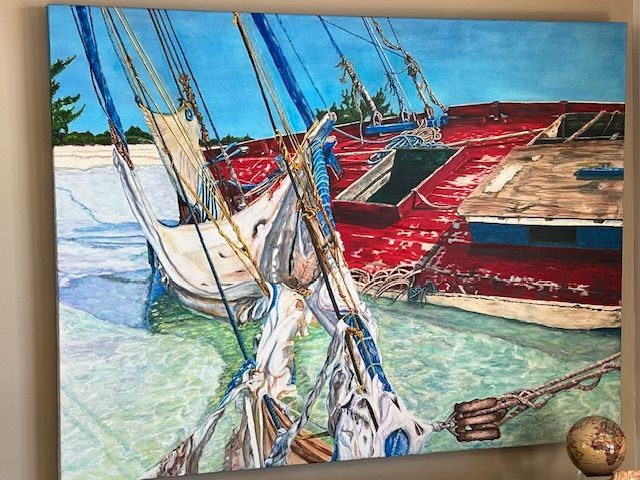 A painting of boats in the water is hanging on a wall.