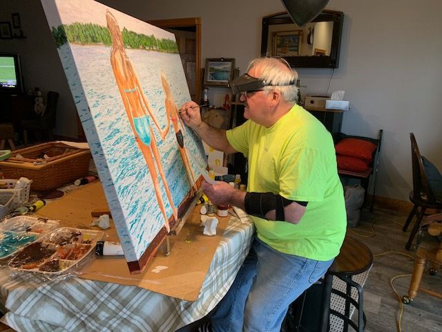 A man in a neon yellow shirt is painting a picture