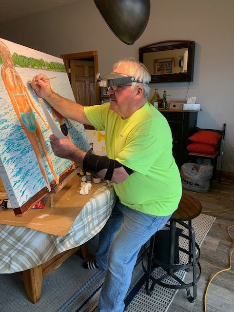 A man in a neon green shirt is painting on an easel