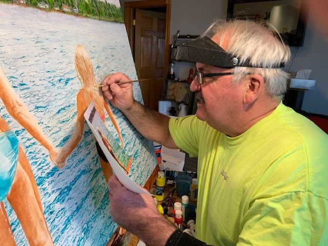 A man is painting a picture of a body of water on a canvas.