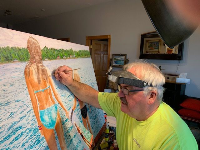 A man is painting a picture of a woman in a bikini