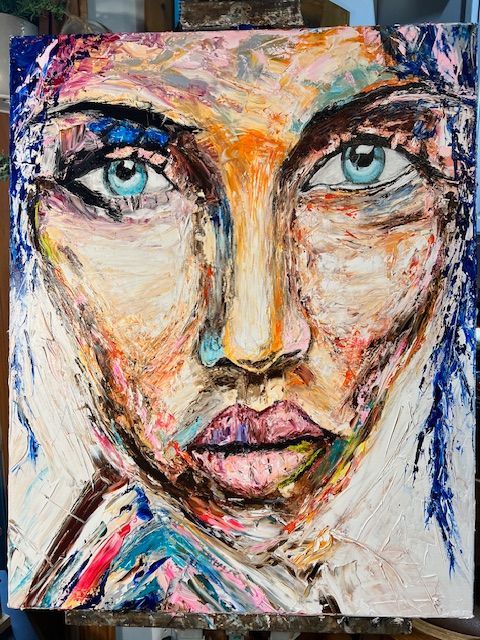 A colorful painting of a woman 's face is on an easel.