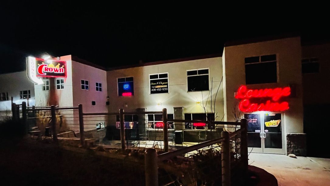 A large white building with a red sign on the side of it is lit up at night.