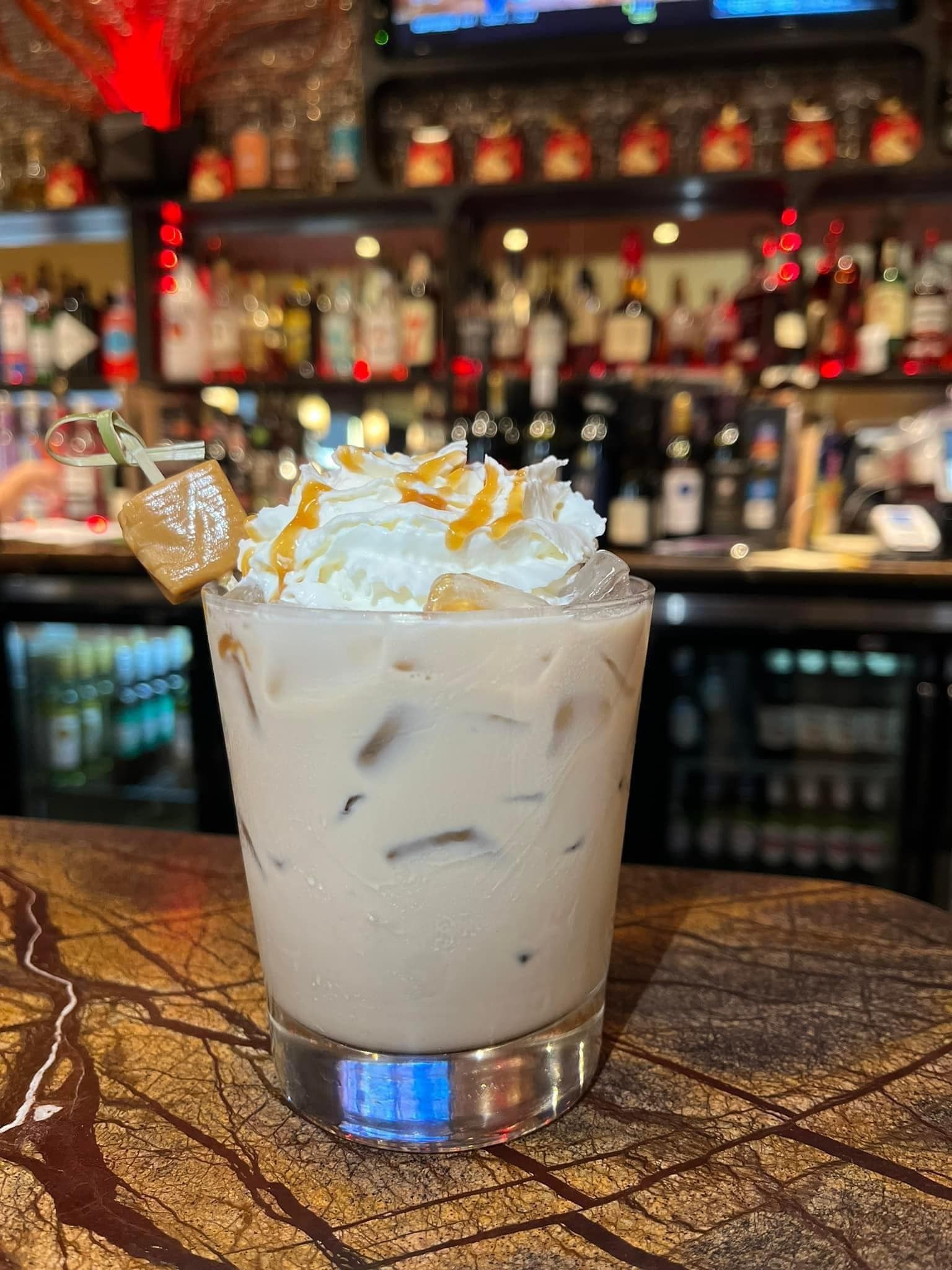 A close up of a drink in a glass on a bar.
