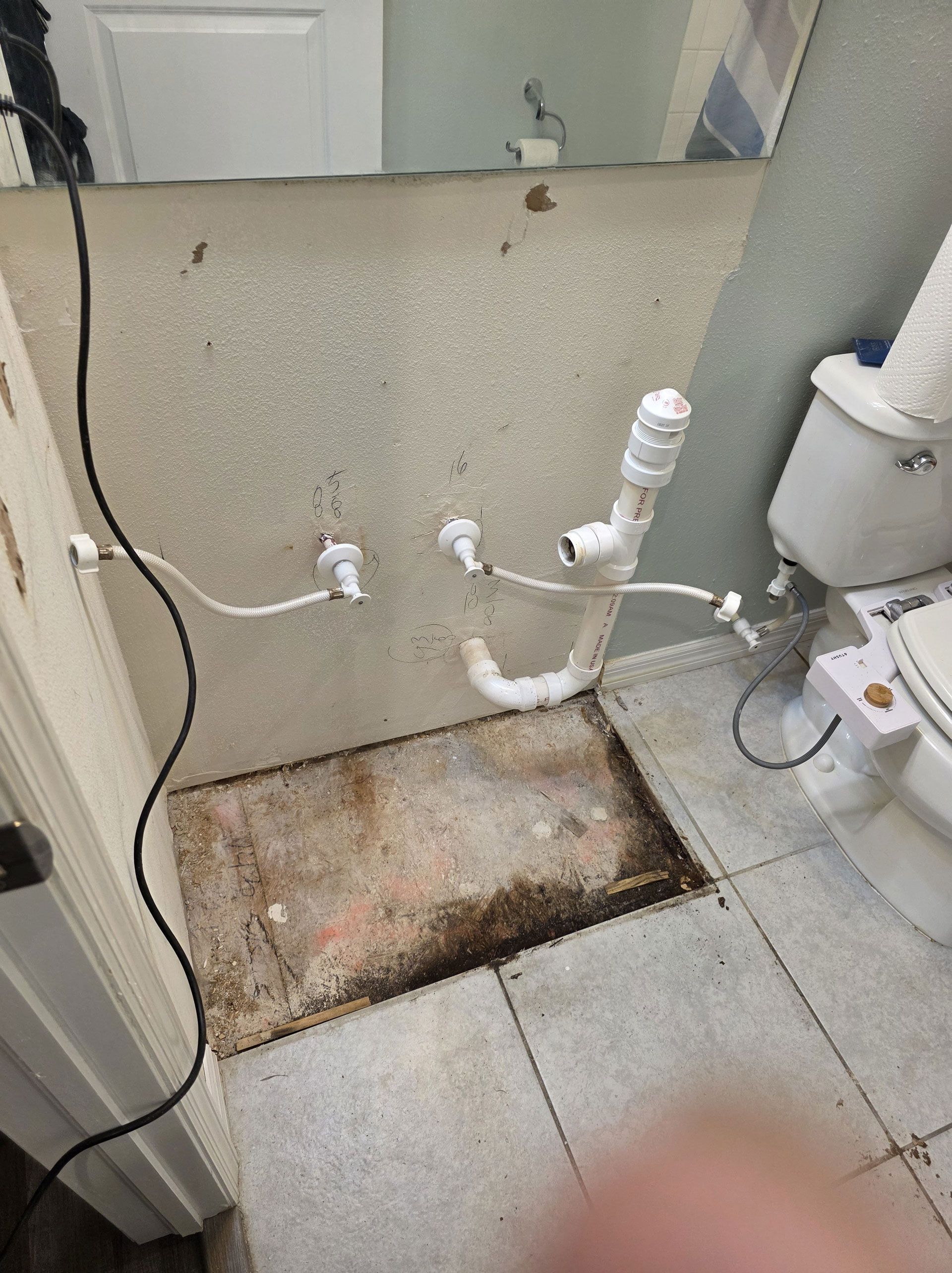 Bathroom with exposed pipes, damaged wall, missing flooring, and a toilet.