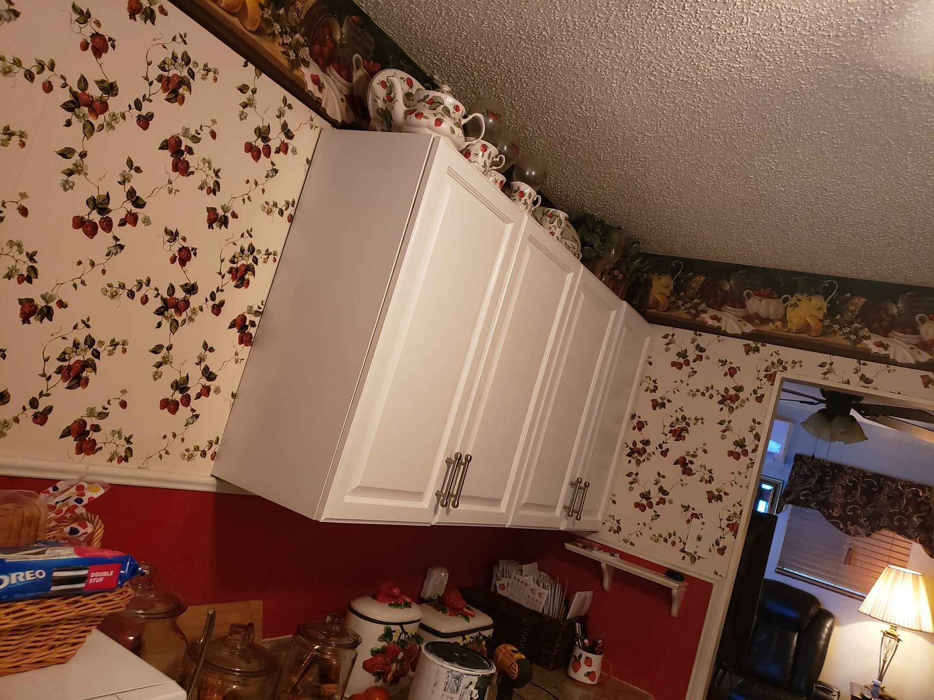 A kitchen with white cabinets and floral wallpaper