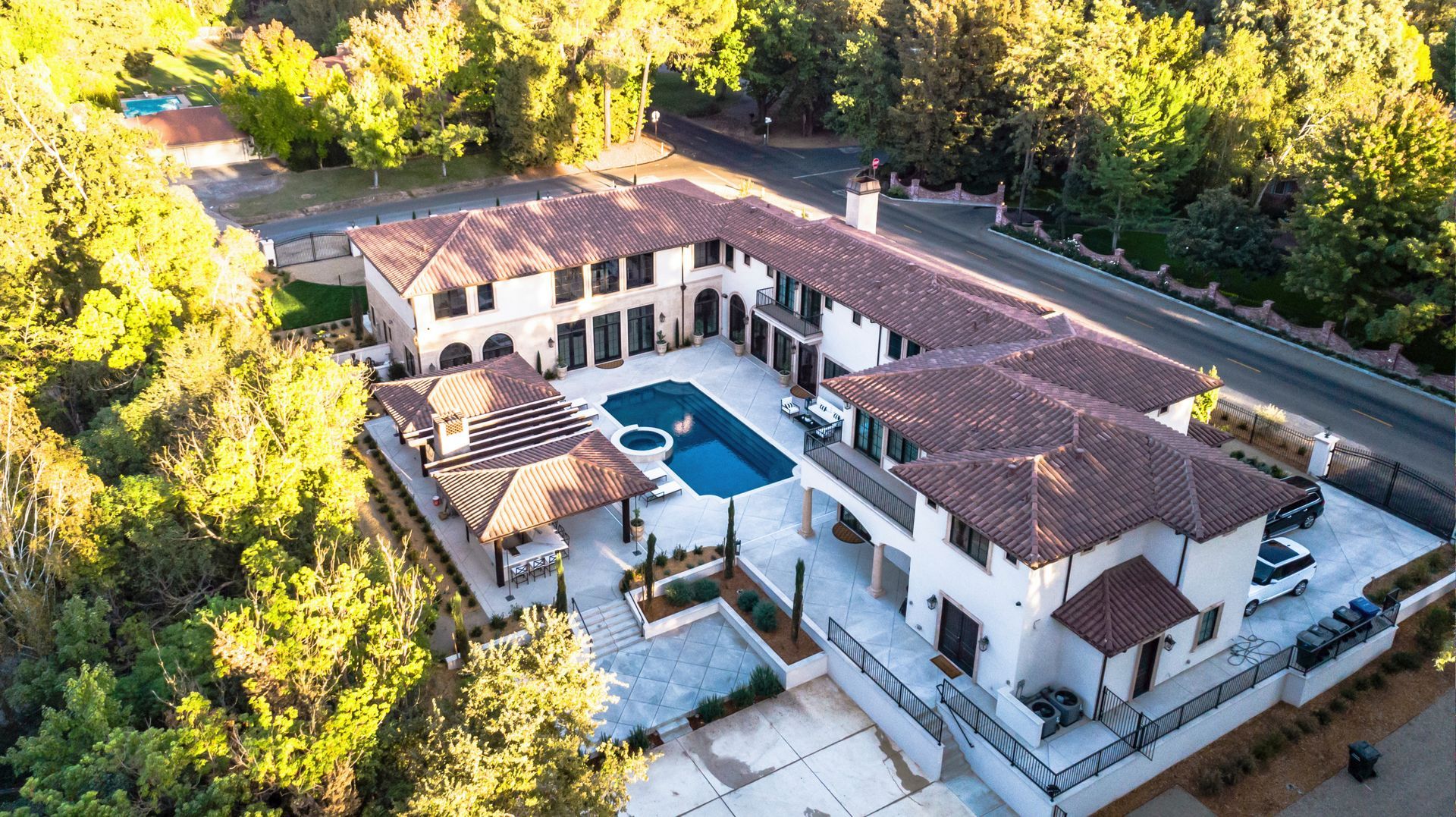 An aerial view of a large house with a pool surrounded by trees.