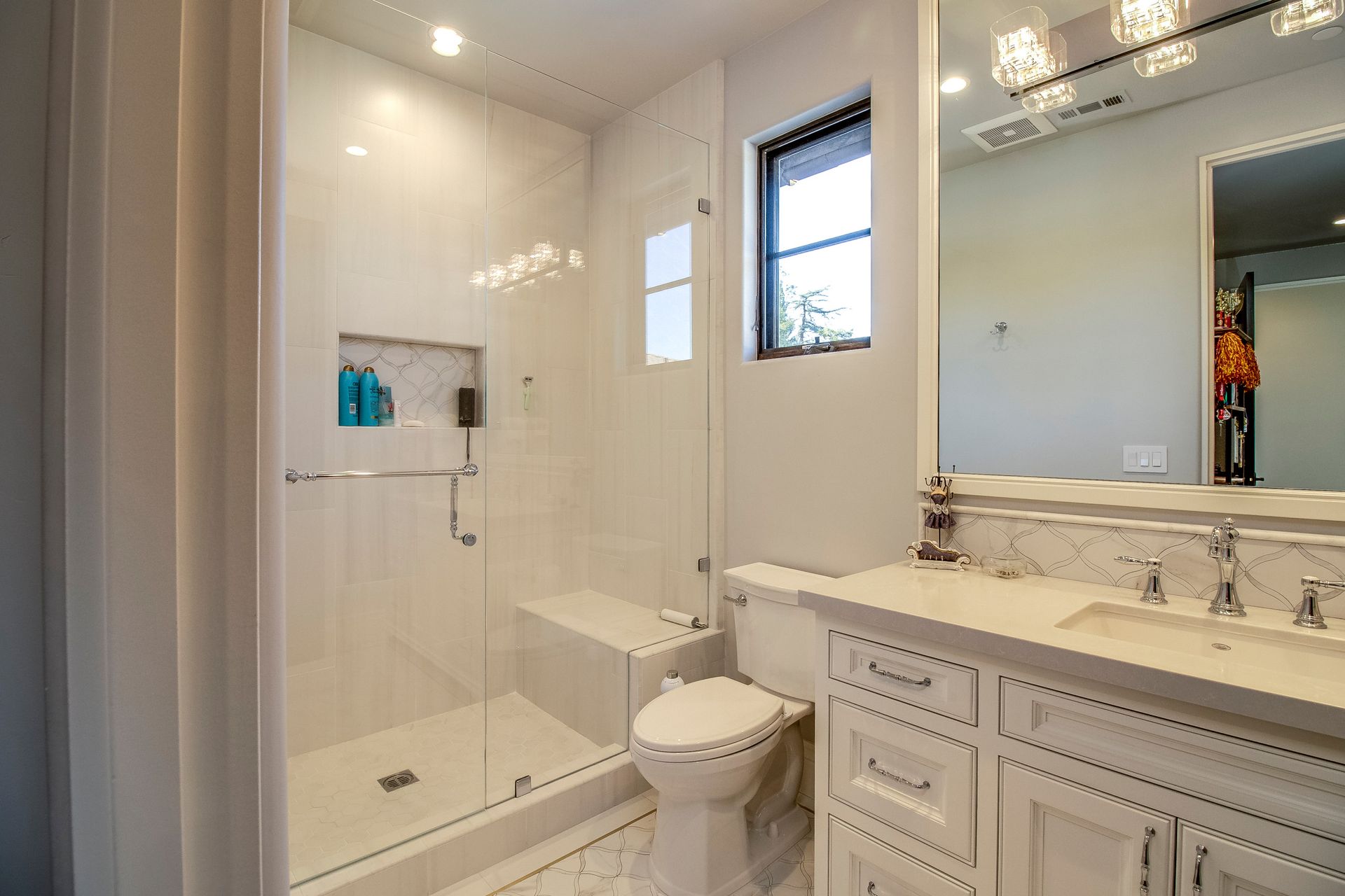 A bathroom with a toilet , sink , shower and mirror.