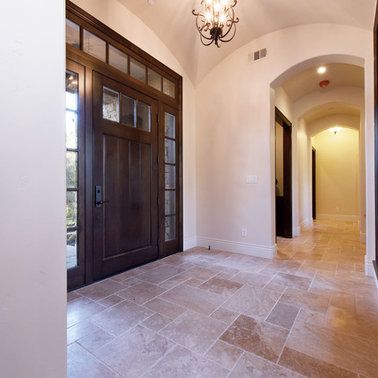 A hallway with a wooden door and a chandelier hanging from the ceiling