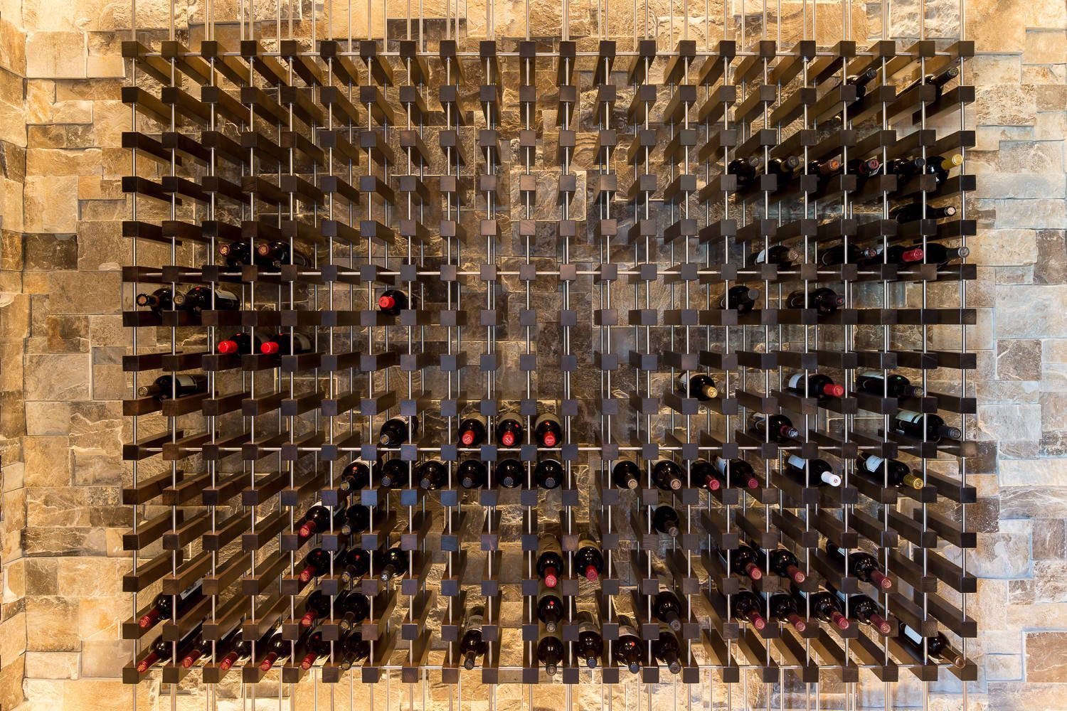 A wine rack is hanging on a brick wall.