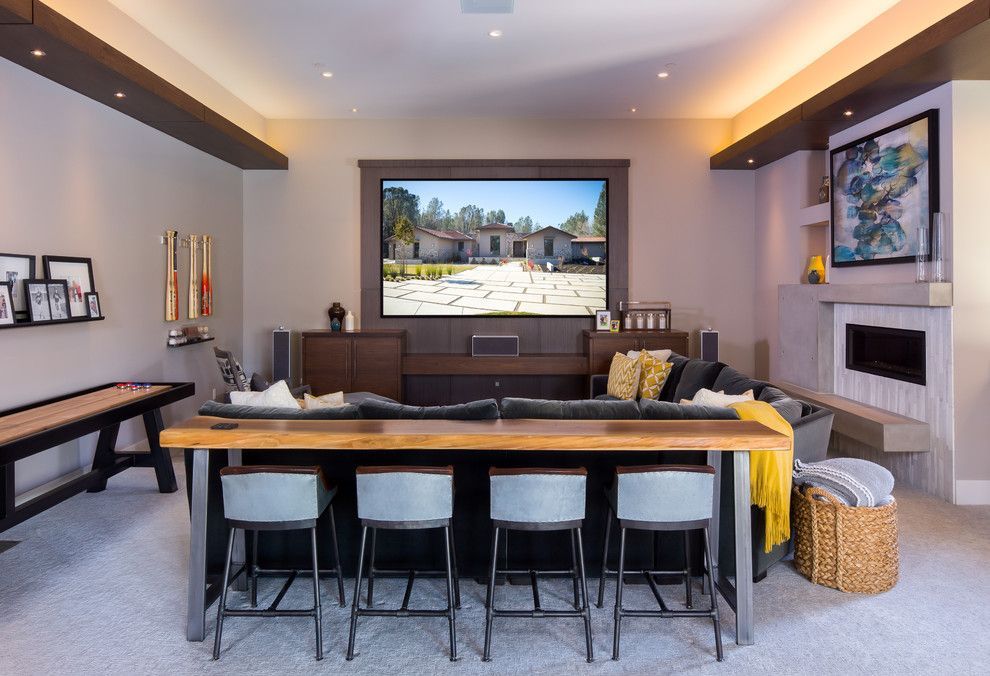 A living room with a couch , stools , a table and a flat screen tv.